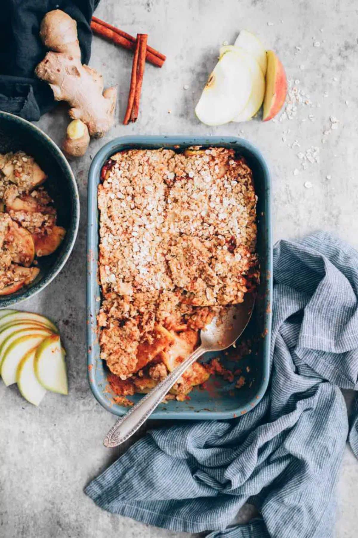 Vegan Sugar-Free Apple Crumble in a blue casserole with a spoon.
