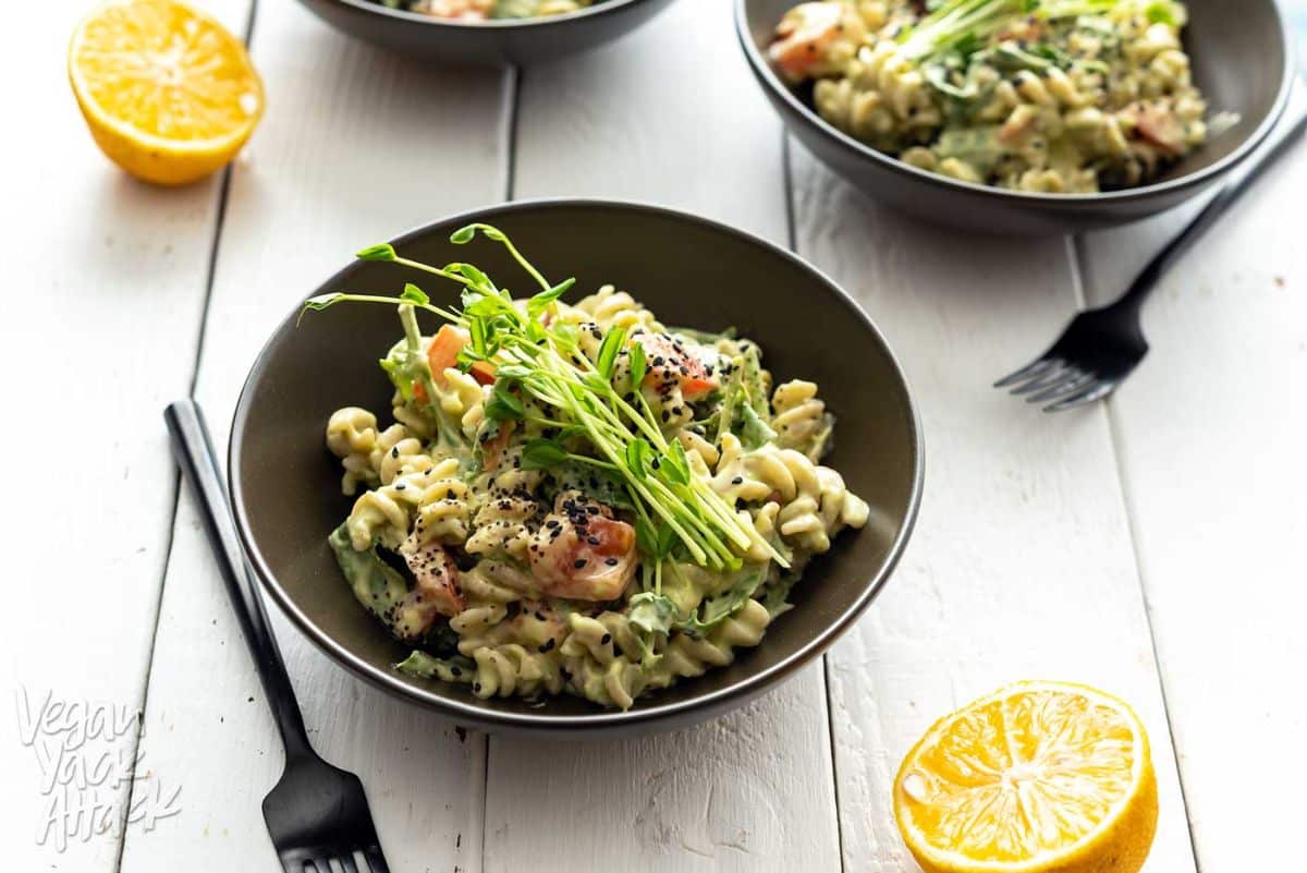 Gluten-free Avocado Tahini Pasta in a black bowl on a wooden table.