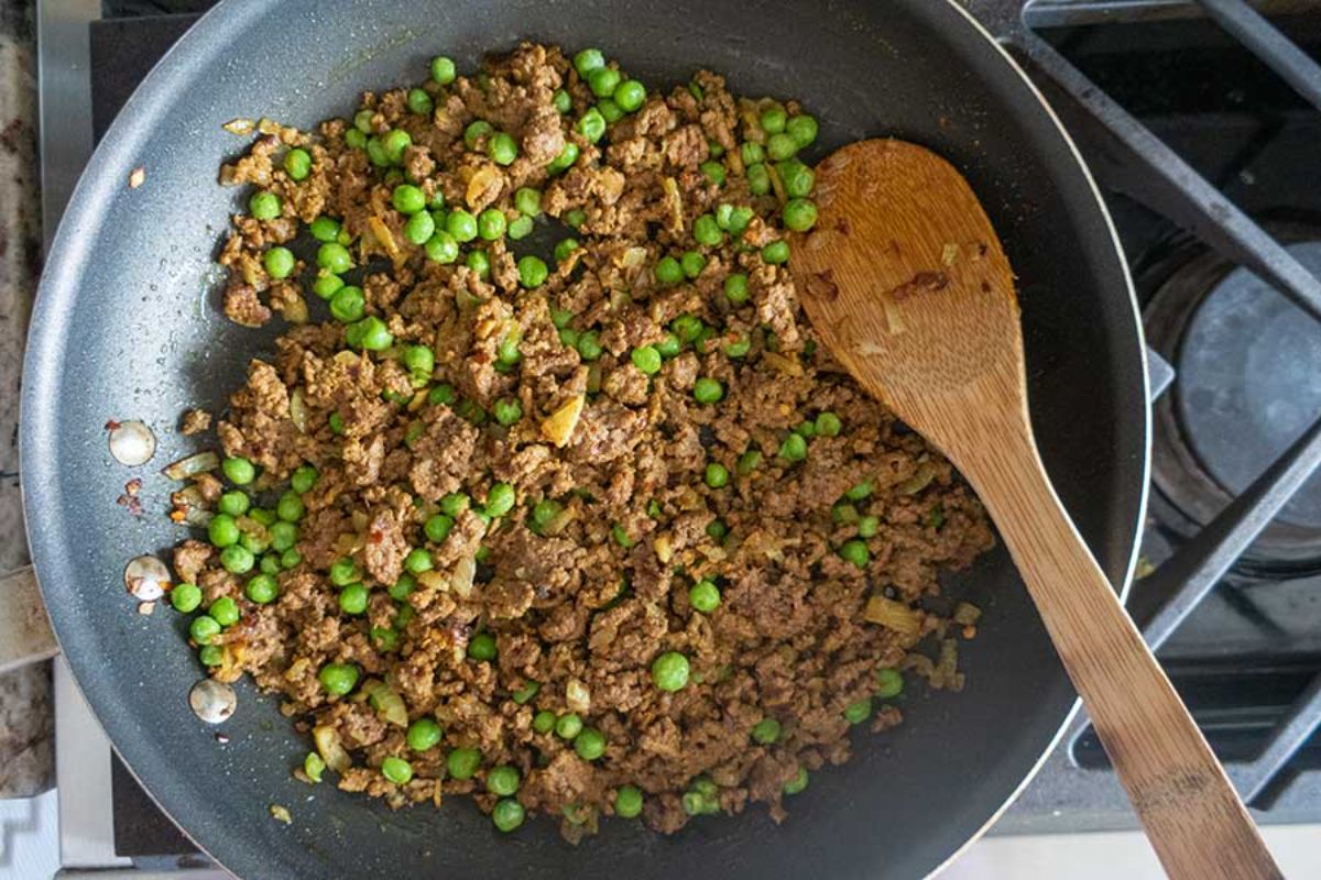 Gluten-Free Spicy Beef in a black pan with a wooden spatula.