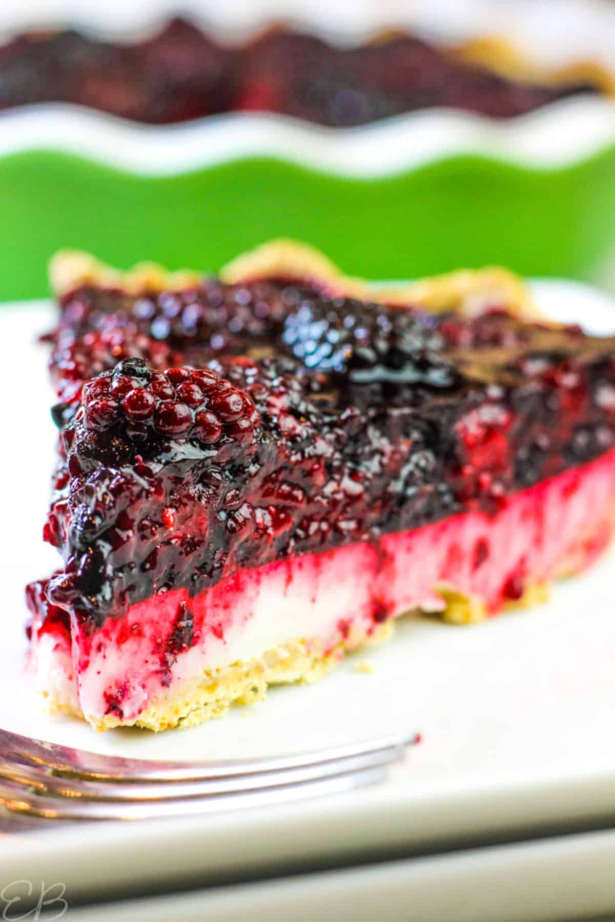 A piece of Blackberry Lemon Cream Pie on a white plate with a fork.