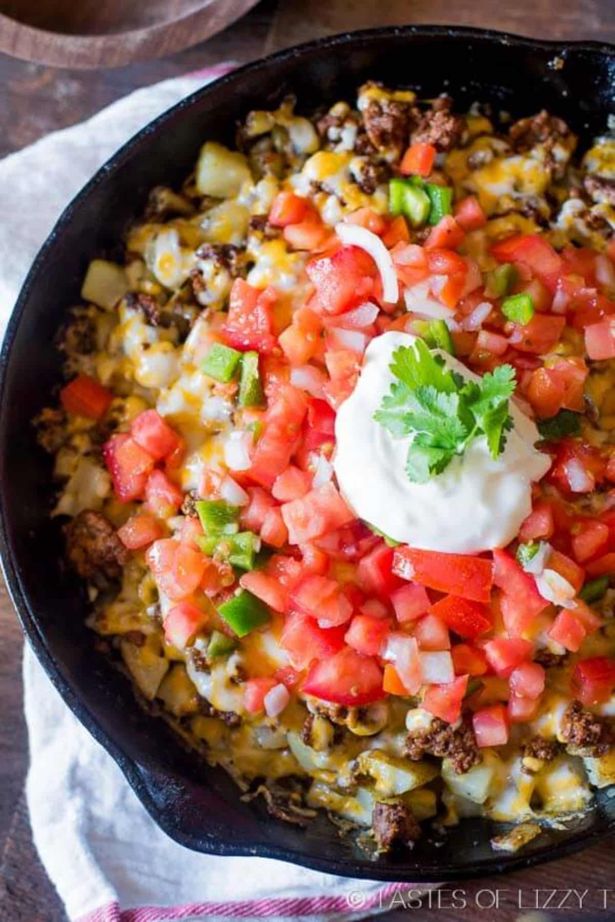 Mexican Potatoes with chopped veggies in a black skillet.