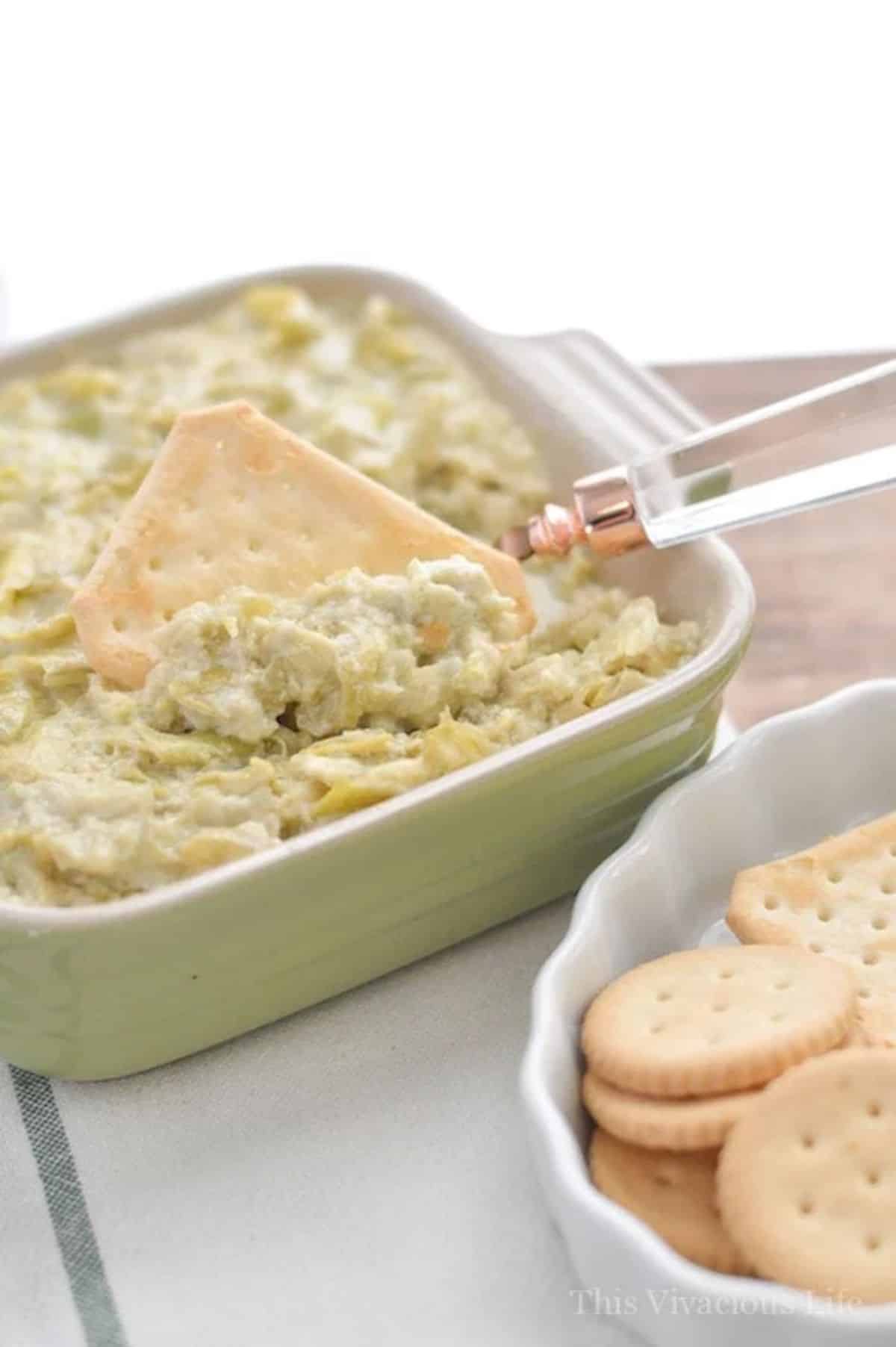 Instant Pot Artichoke Dip in a white bowl with a cracker.
