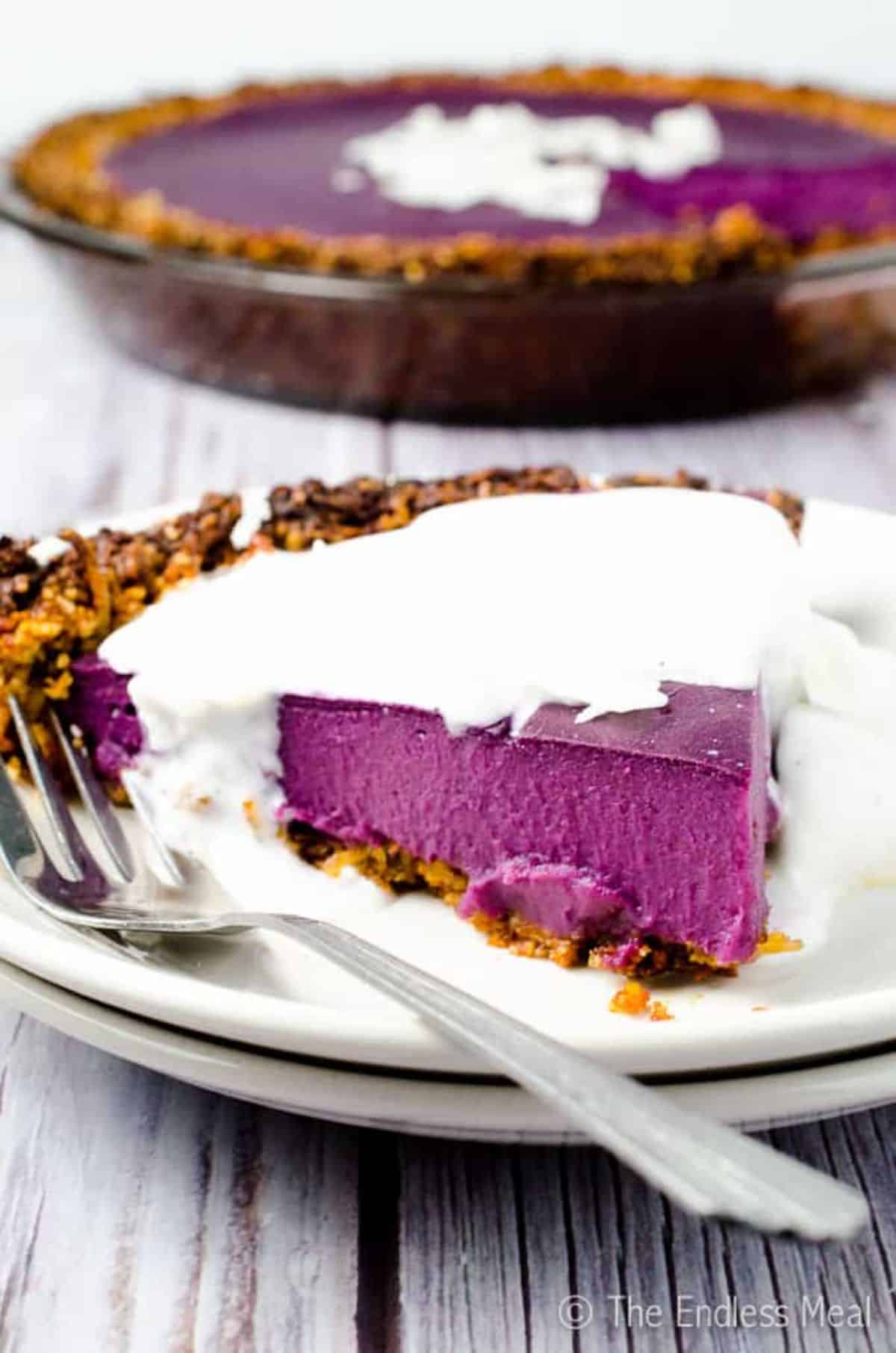 A piece of Vegan Purple Sweet Potato Pie with Coconut Almond Crust on a plate with a fork.
