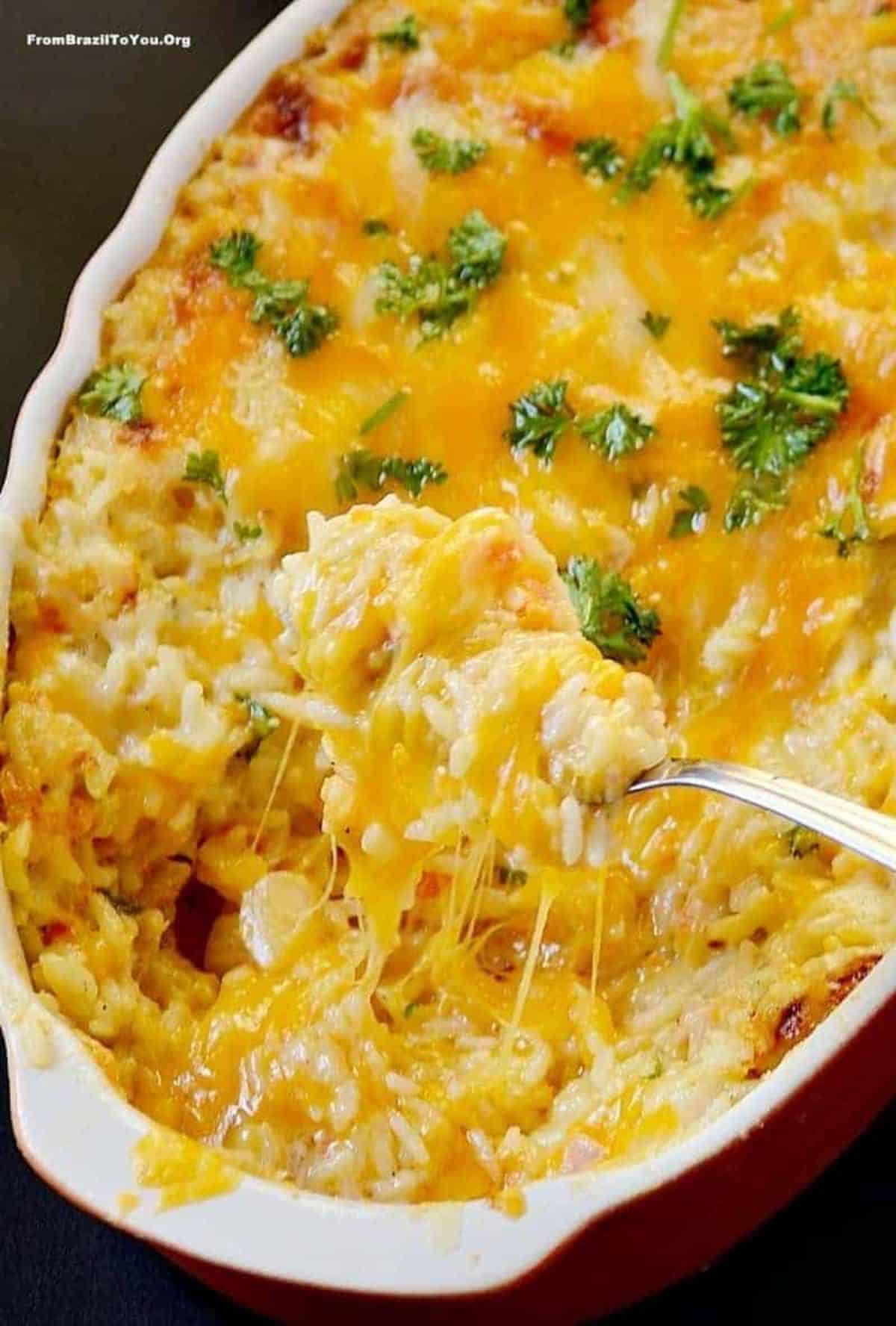 Ham and Cheese Baked Rice in a red-white casserole picked by a fork.