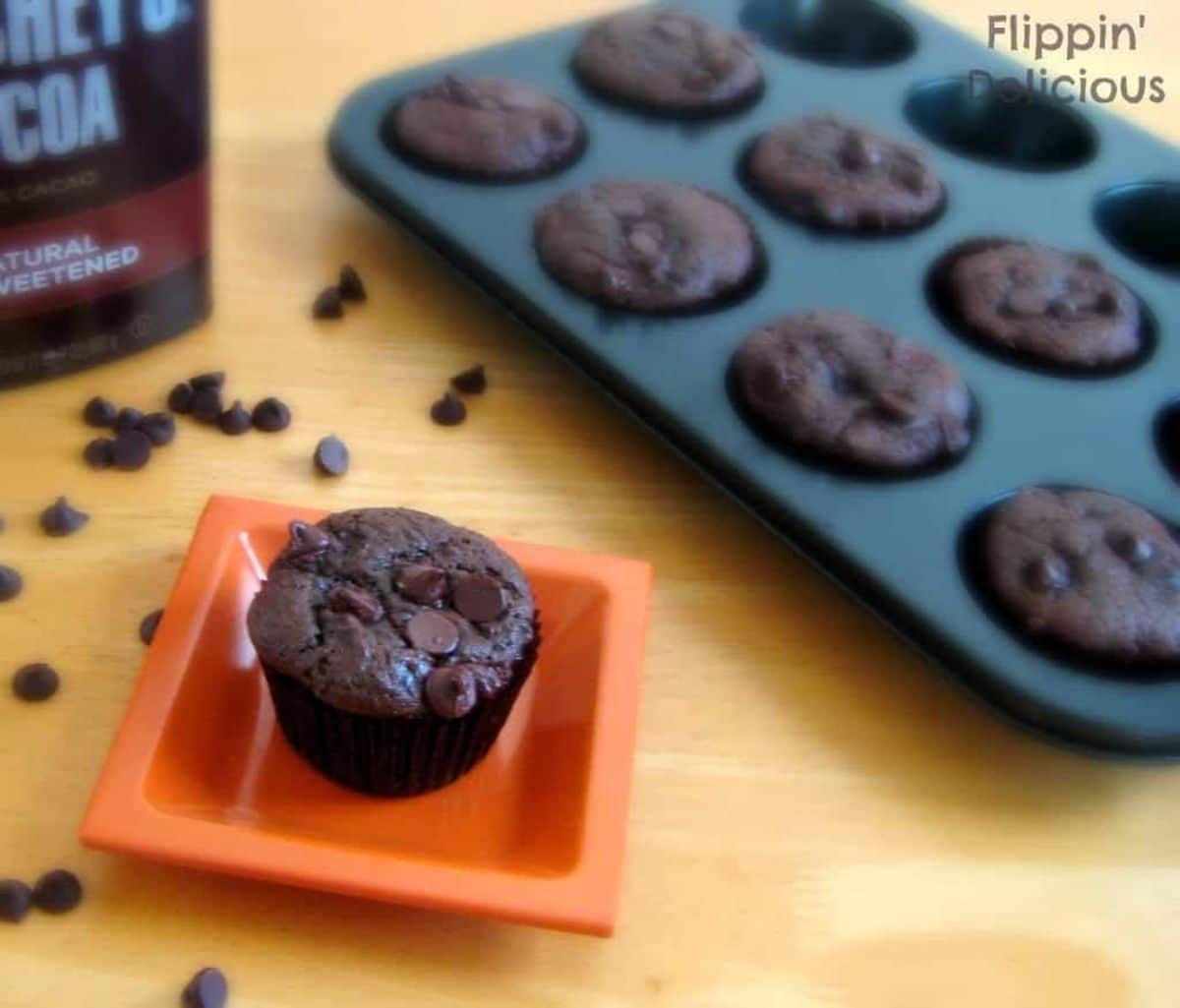 Gluten-free Chocolate Chocolate Chip Muffins in a tray and on a small red plate.