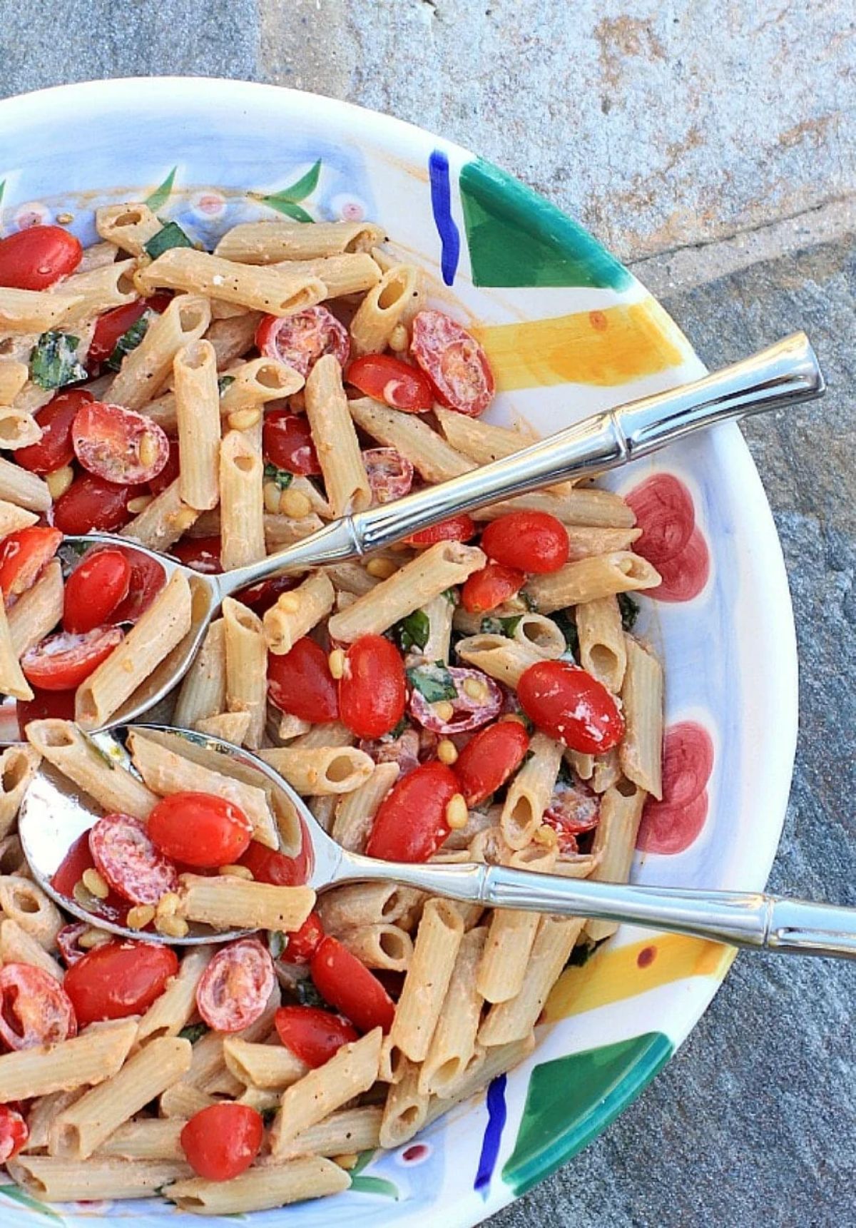 Gluten-free Pasta Salad with Tomatoes, Basil, and Fresh Ricotta in a colorful bowl with two spoons.