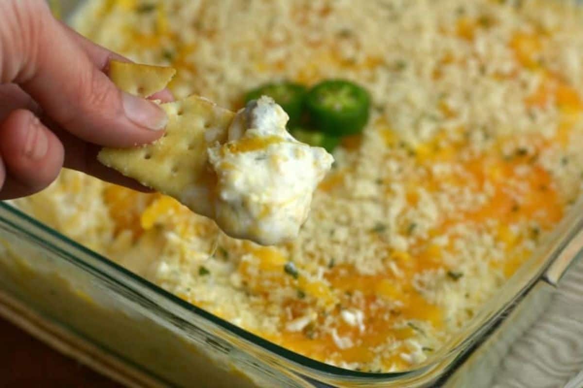 Jalapeno Hot Popper and Chicken Dip in a glass casserole scooped on a cracker.