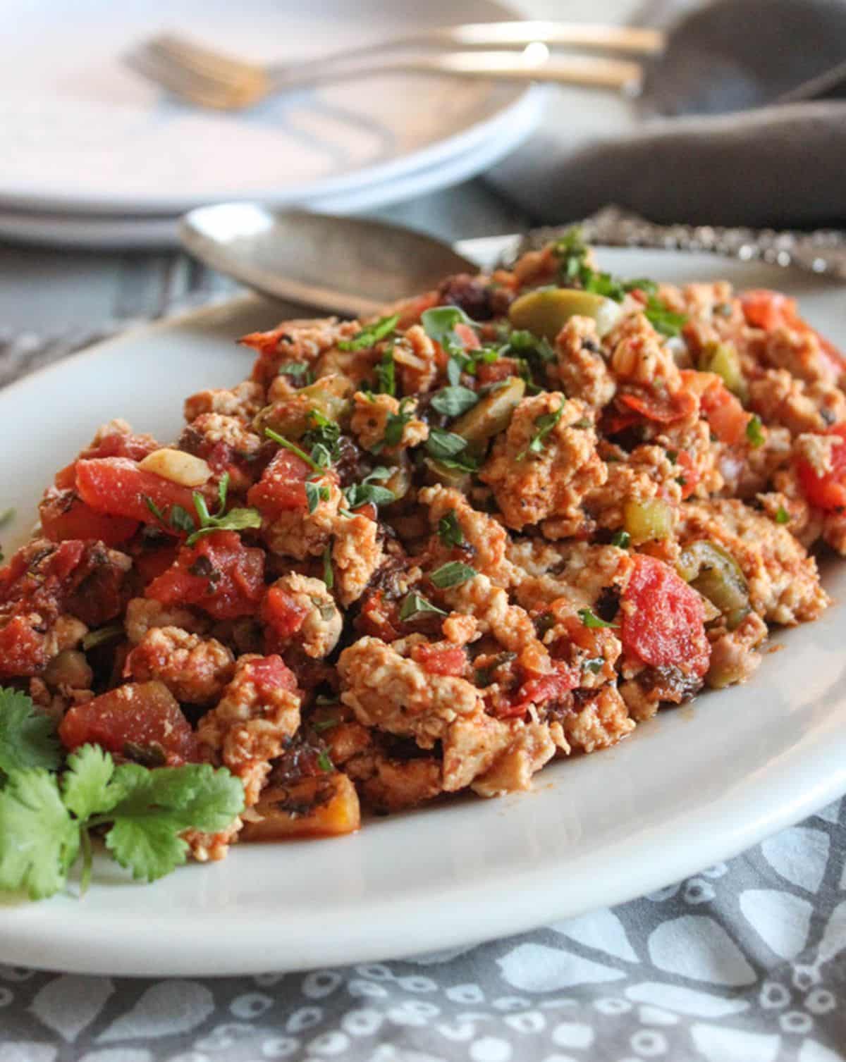 Ground Chicken Picadillo on a white plate with a spoon.