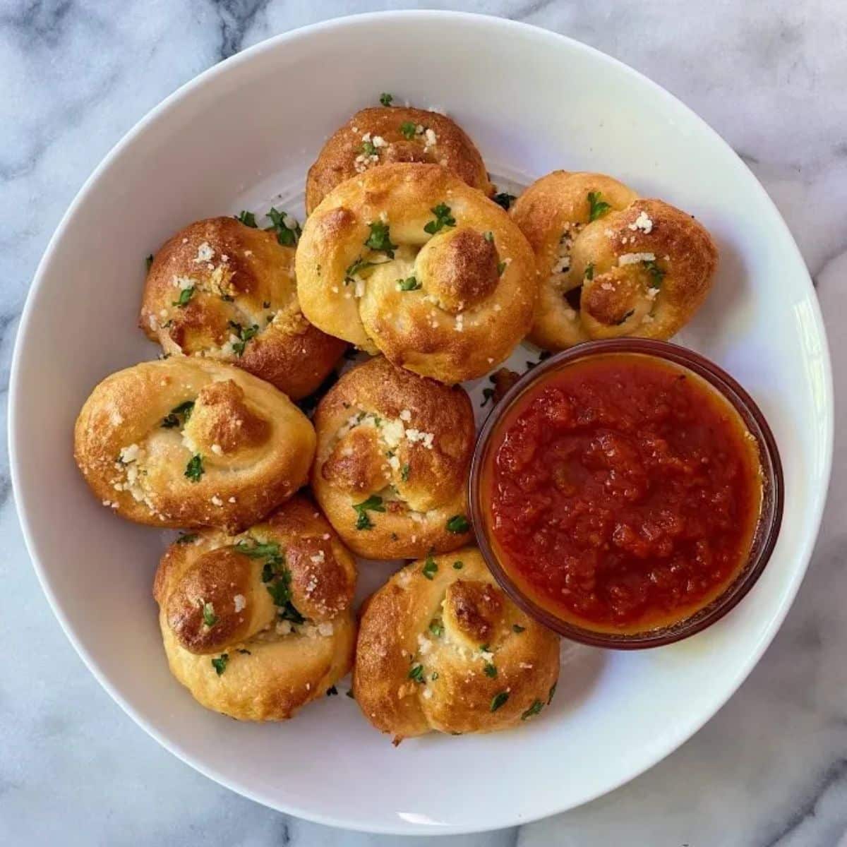 Garlic Knots with a dip in bowl in a white bowl.