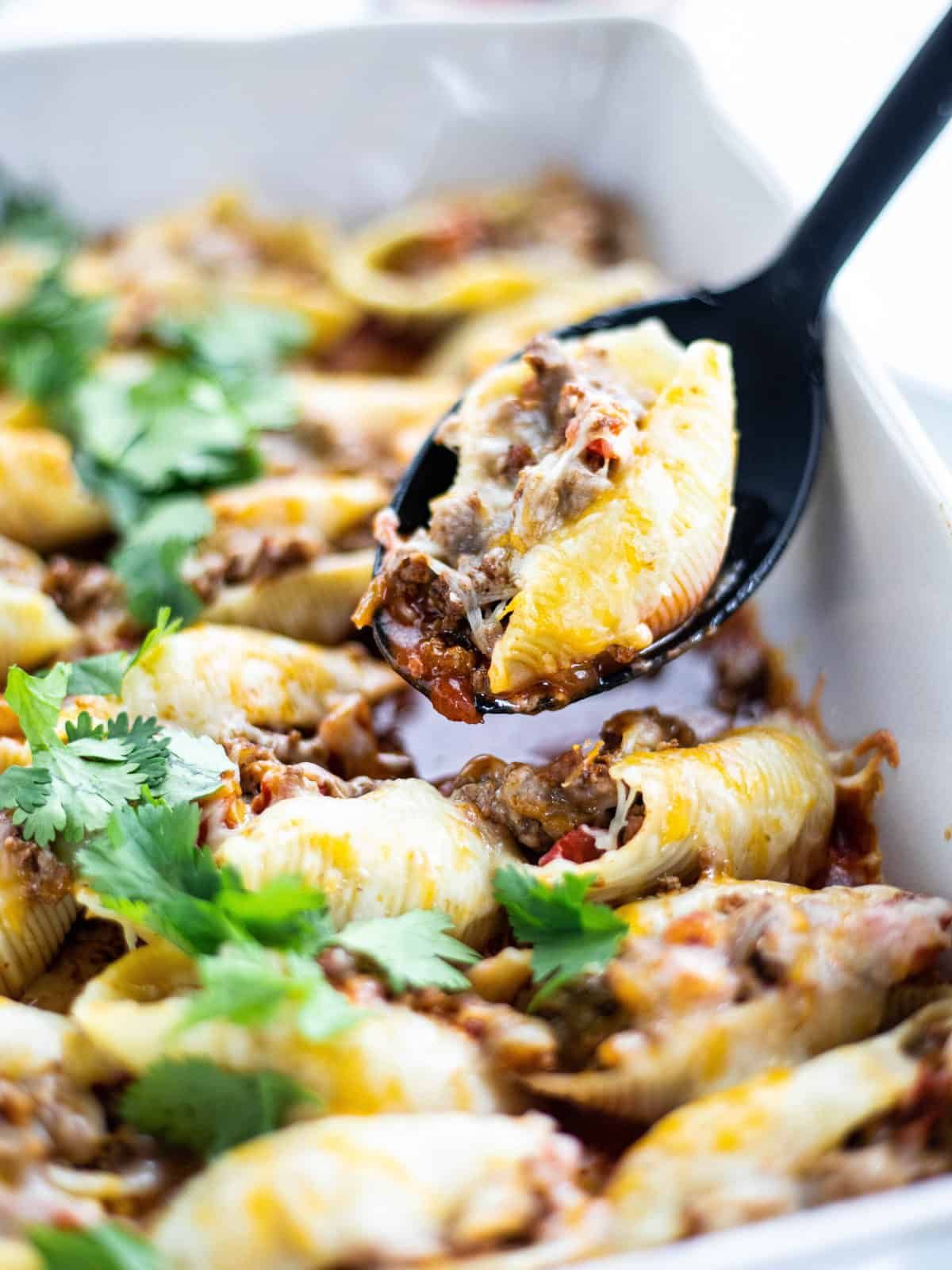 Mexican Shells with Ground Beef in a casserole scooped by a spoon.