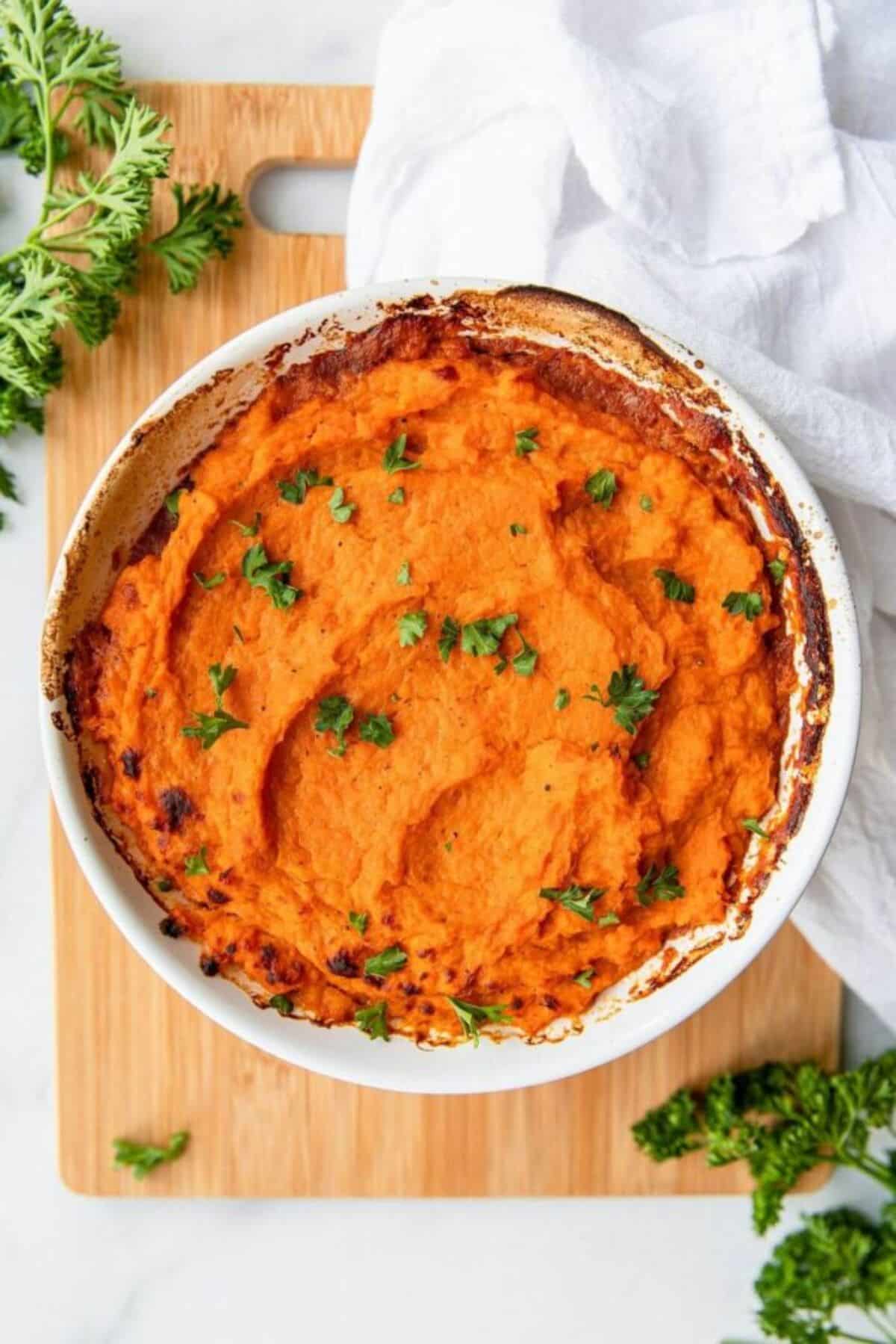 Sweet Potato Chicken Shepherd's Pie in a white tray on a wooden cutting board.