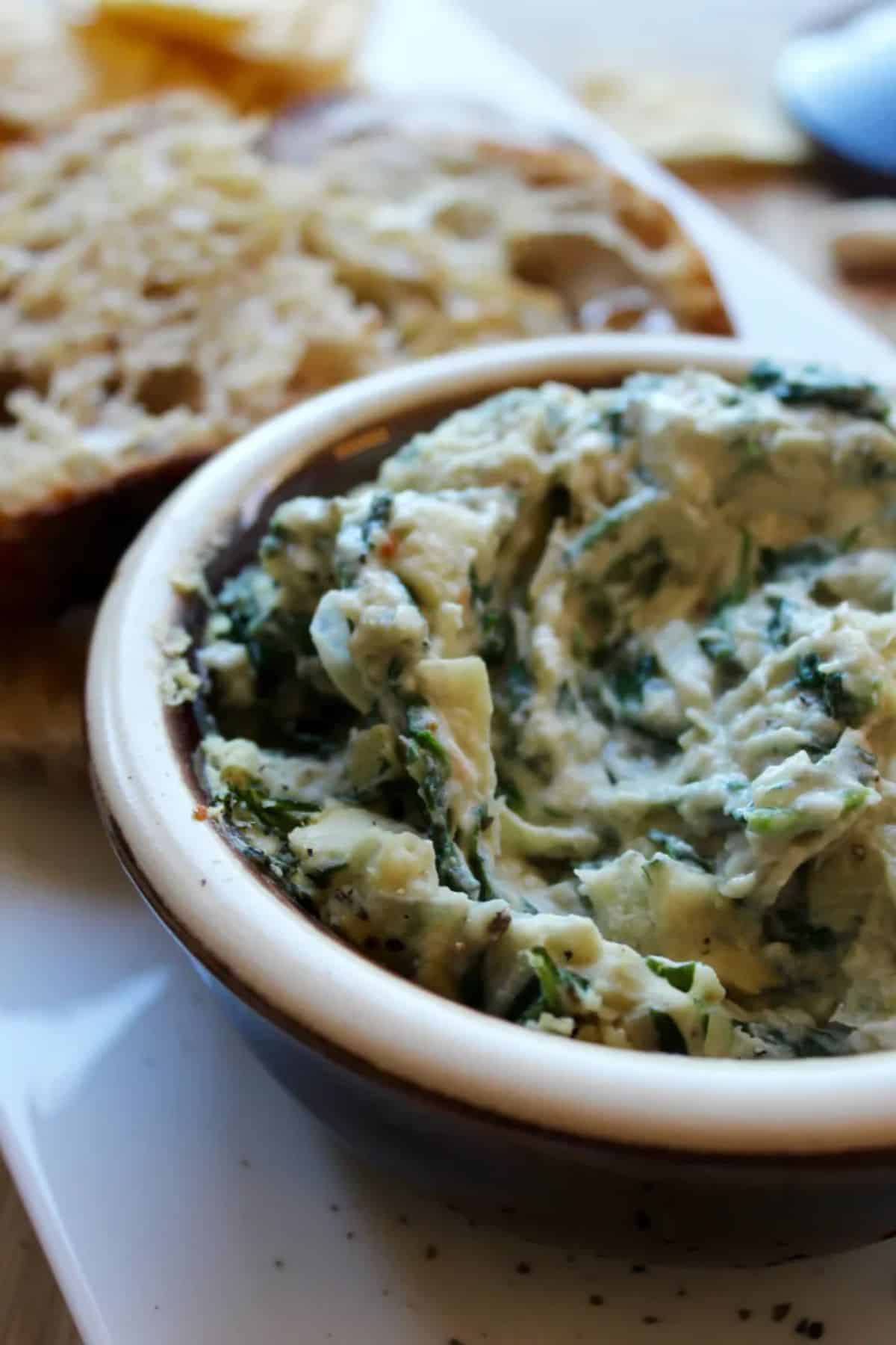 Hot Spinach Artichoke and White Bean Dip in a brown bowl.