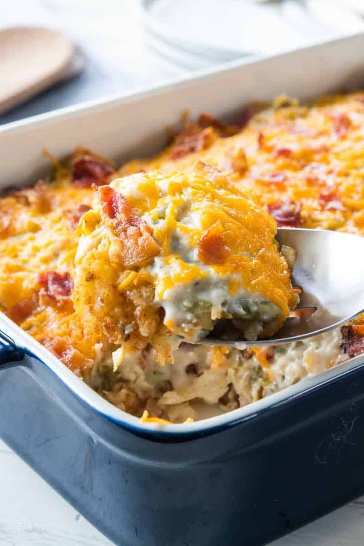 Chicken Bacon Ranch Tatertot in a white-blue casserole scooped by a spoon.