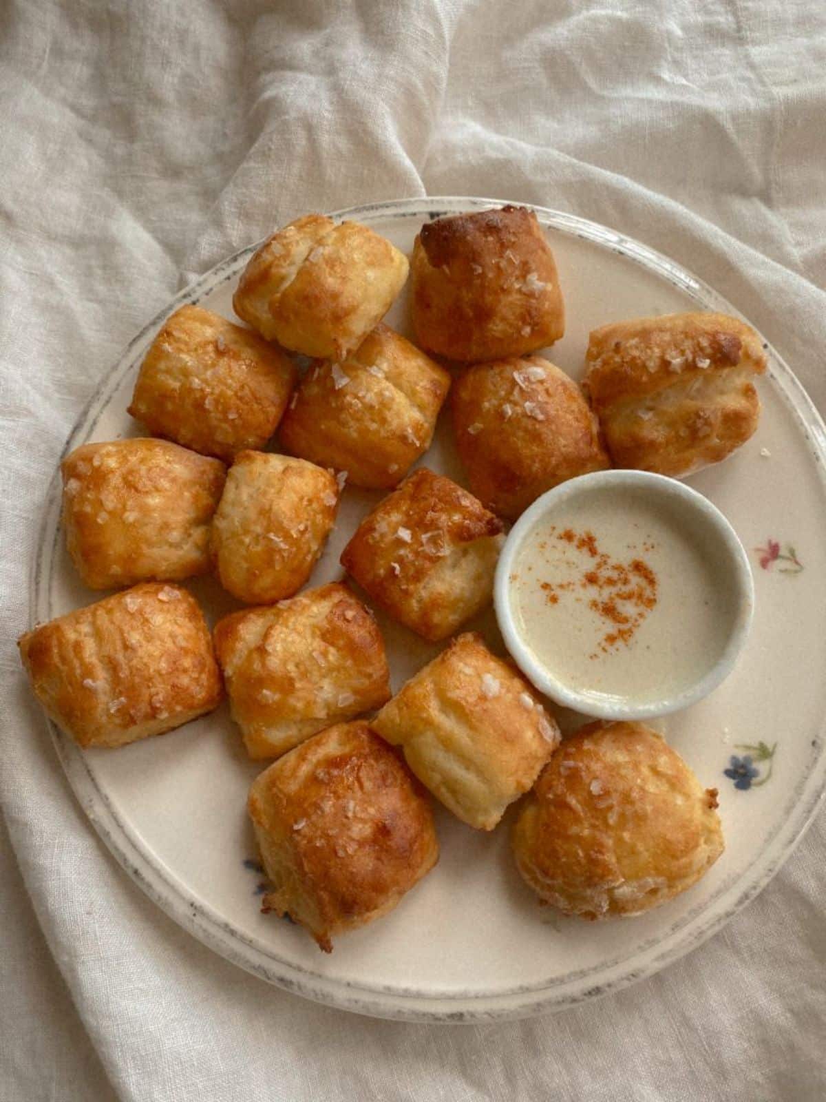 Easy No-Yeast Gluten-Free Pretzel Bites with a dip in bowl on a white plate.