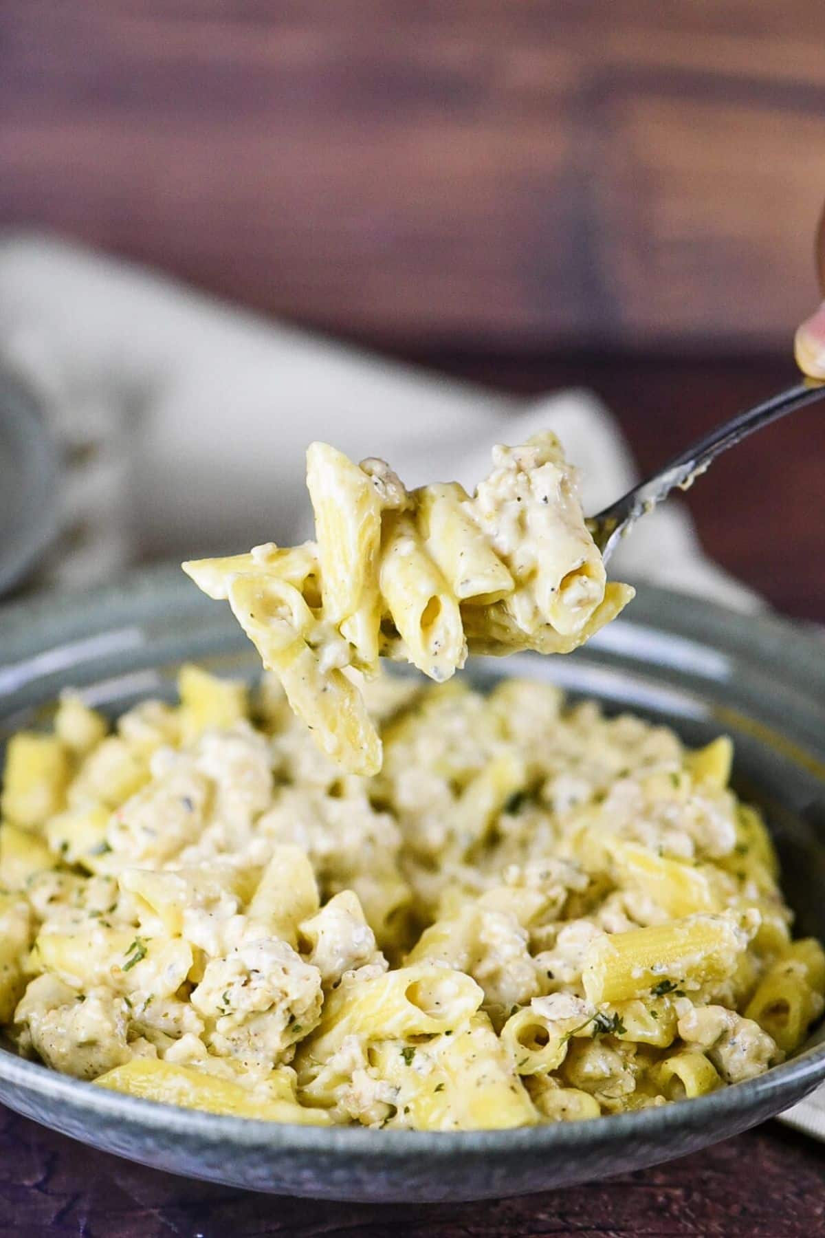 Gluten-Free Chicken Gouda Penne Pasta on a gray plate scooped by a spoon.