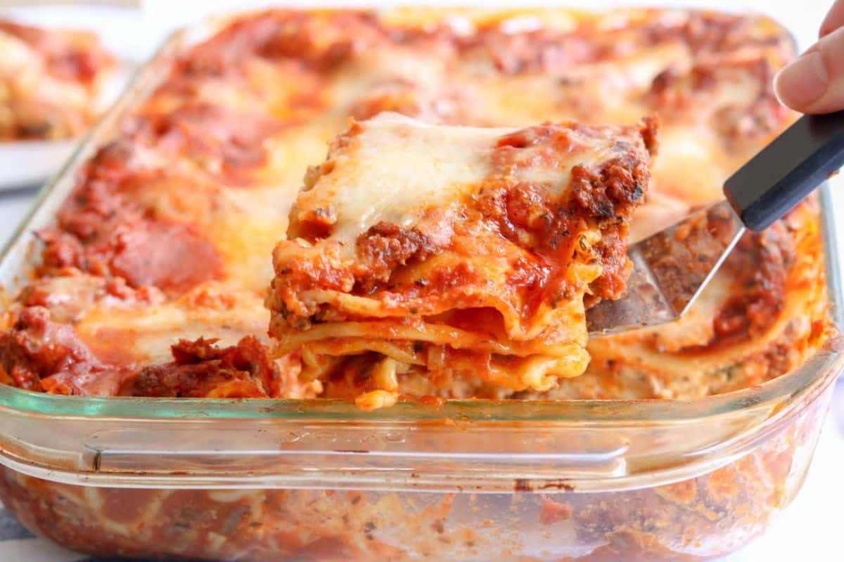 Gluten-free Beef and Mushroom Lasagna in a glass casserole picked by a spatula.
