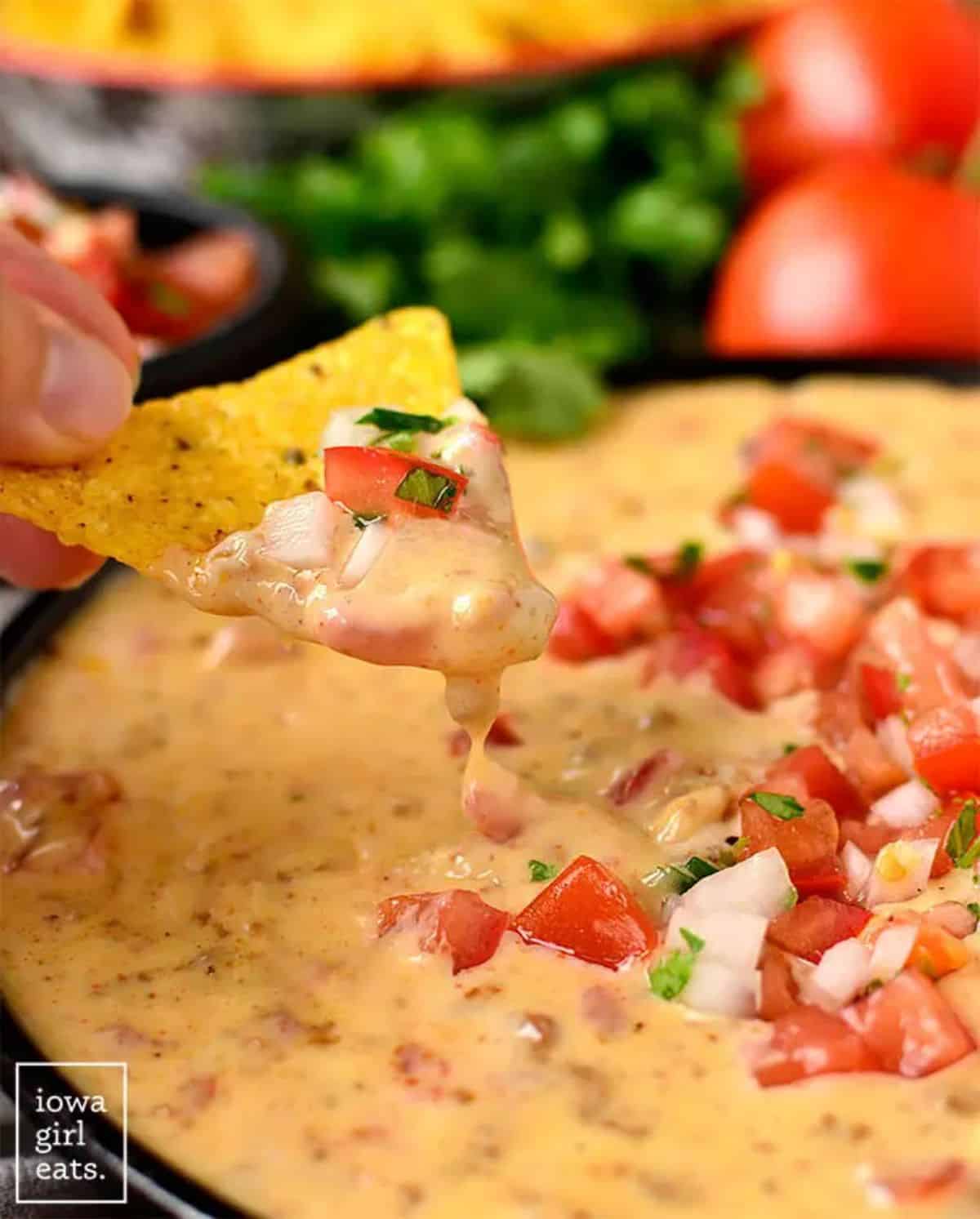 Chorizo Queso Dip in a black bowl scooped with a chip.