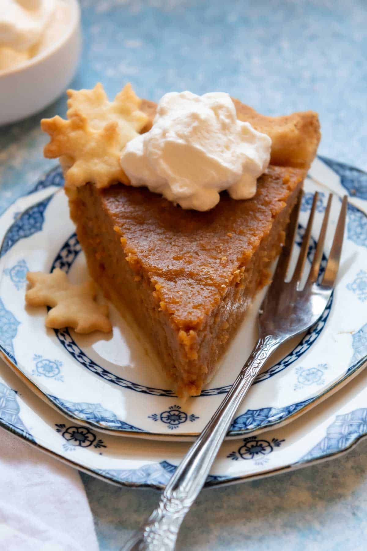 A piece of Gluten-Free Sweet Potato Pie with Flaky Crust on a blue plate with a fork.