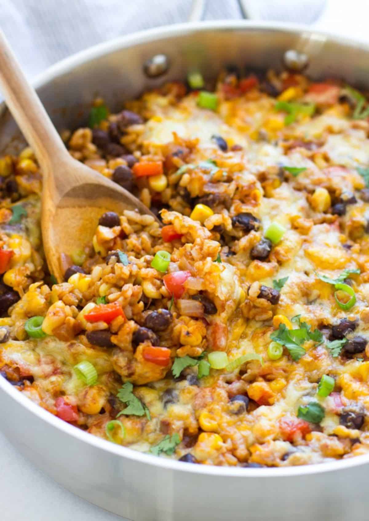 One Pot Mexican Rice in a pan with a wooden spatula.