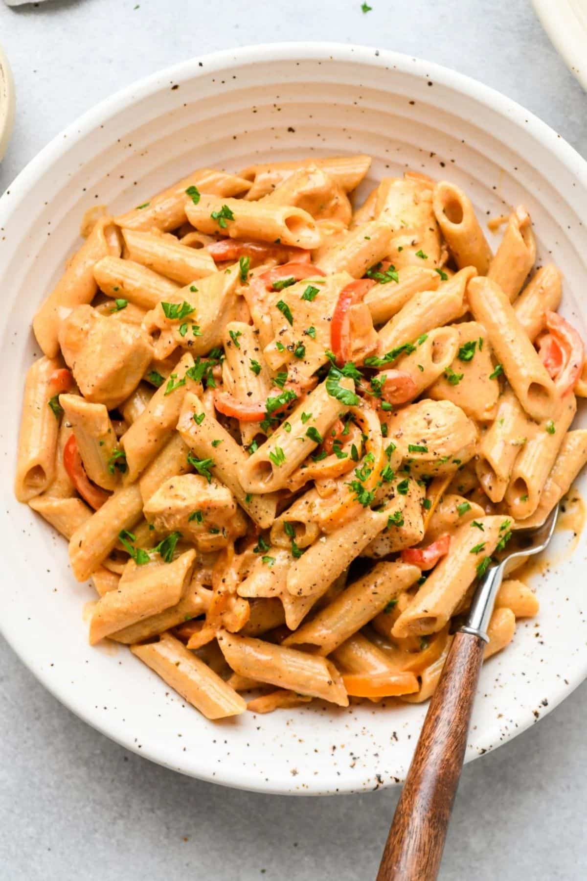 Creamy Cajun Chicken Pasta on a white plate with a fork.