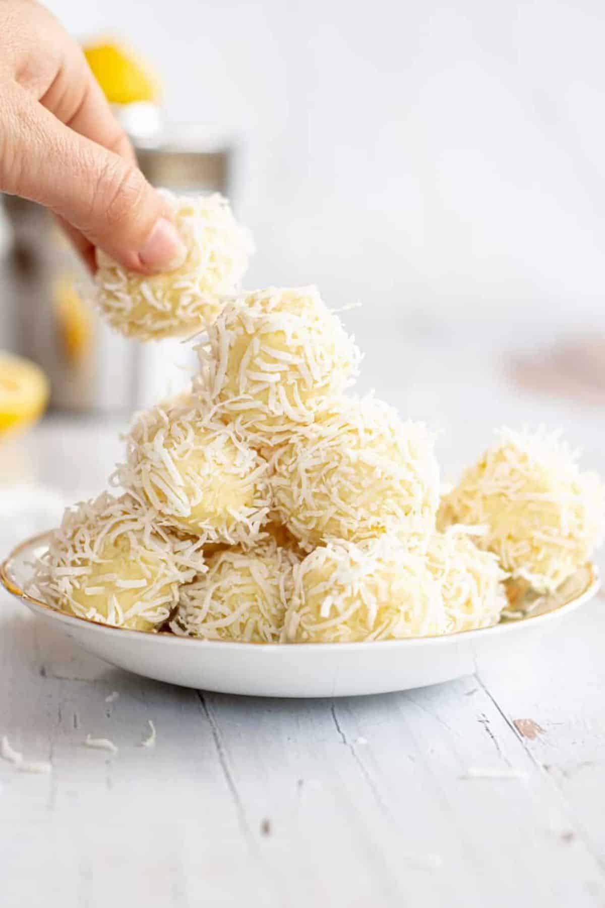 Lemon White Chocolate Truffles on a plate, one picked by hand.