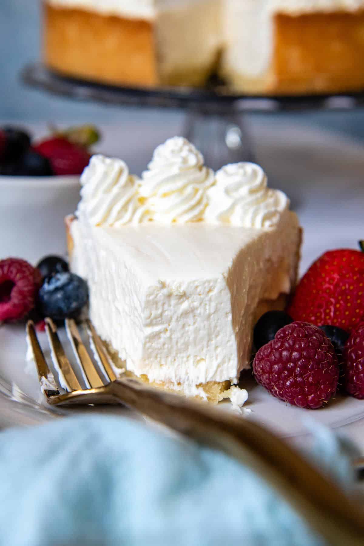 Gluten-Free Cheesecake with fruits on a white plate with a fork.