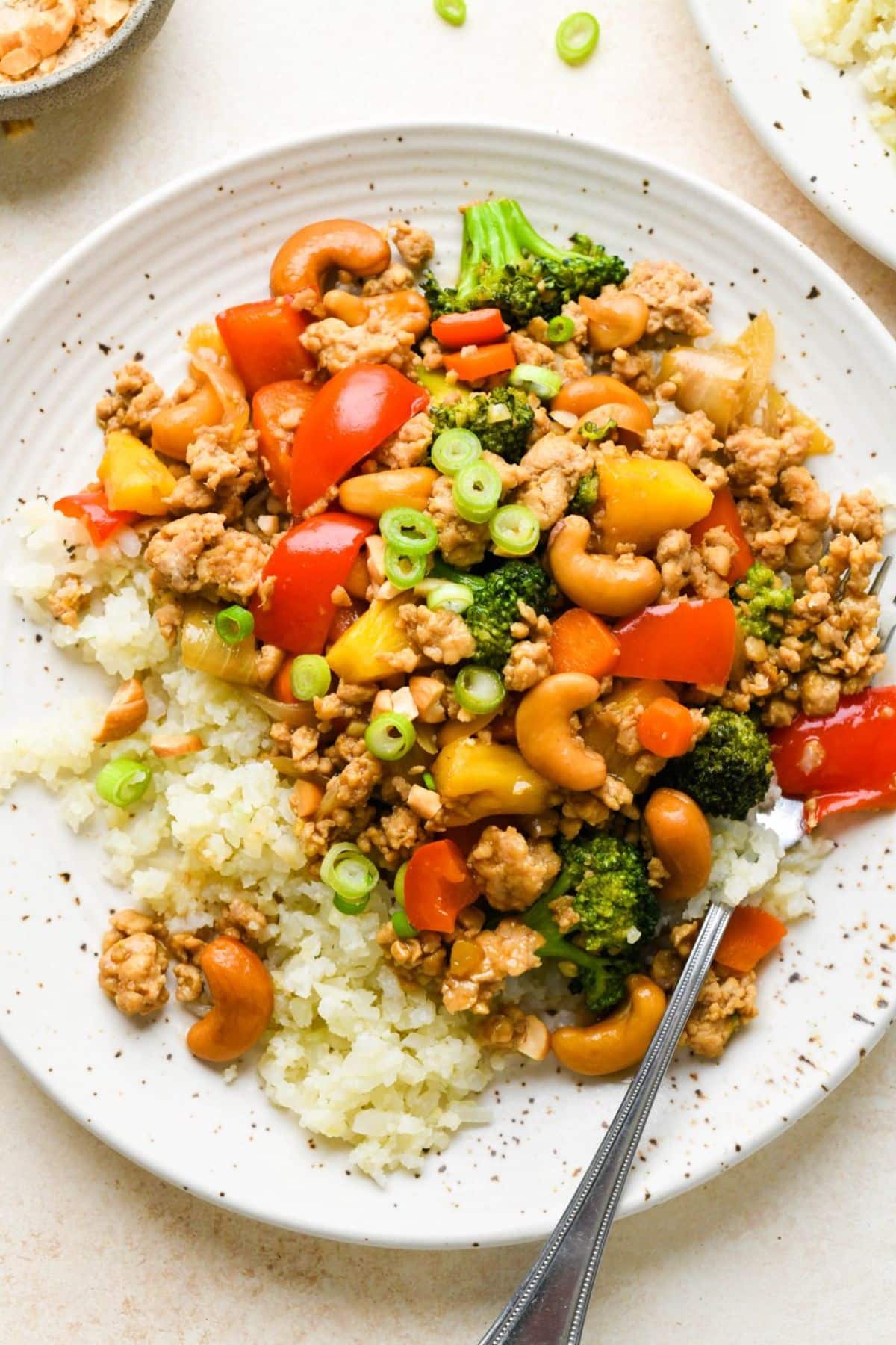 Healthy Cashew Chicken Stir Fry on a white plate with a fork.
