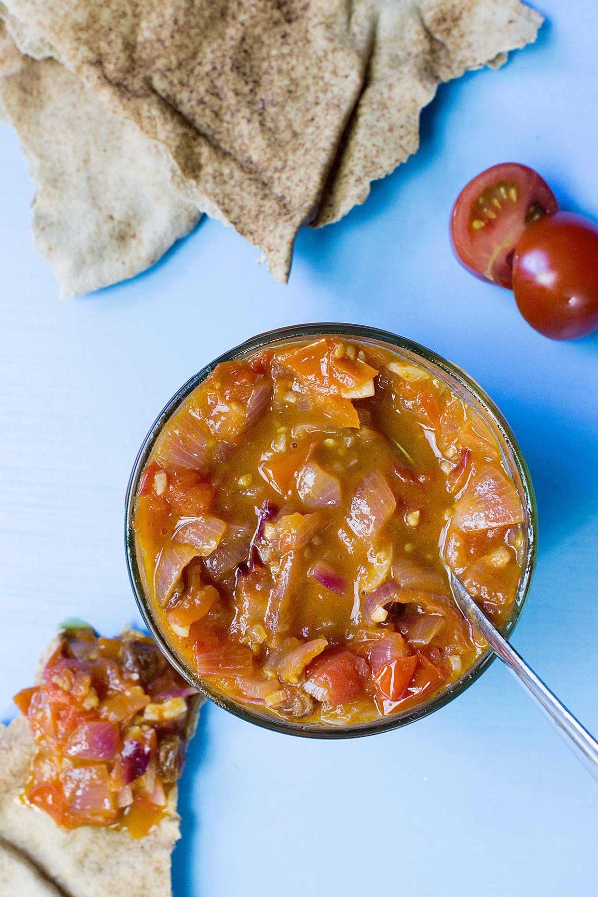 Tomato Chutney in a glass bowl with a spoon.