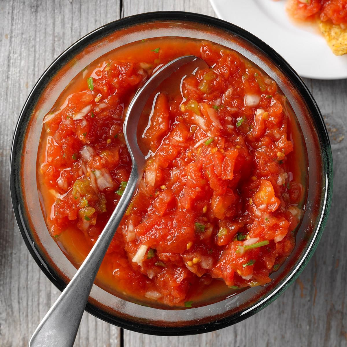 Mexican Homemade Salsa in a glass bowl with a spoon.