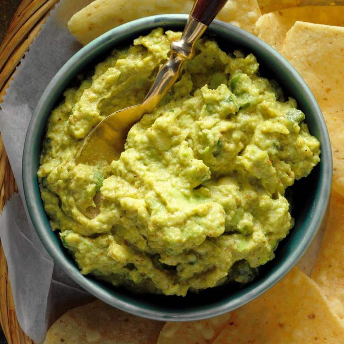 Effortless Guacamole dip in a blue bowl with a spoon.