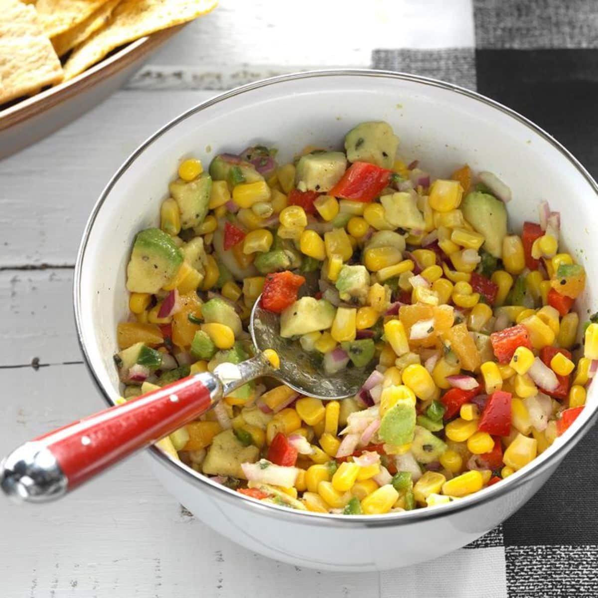 Fresh Corn Avocado Dip in a white bowl with a spatula.