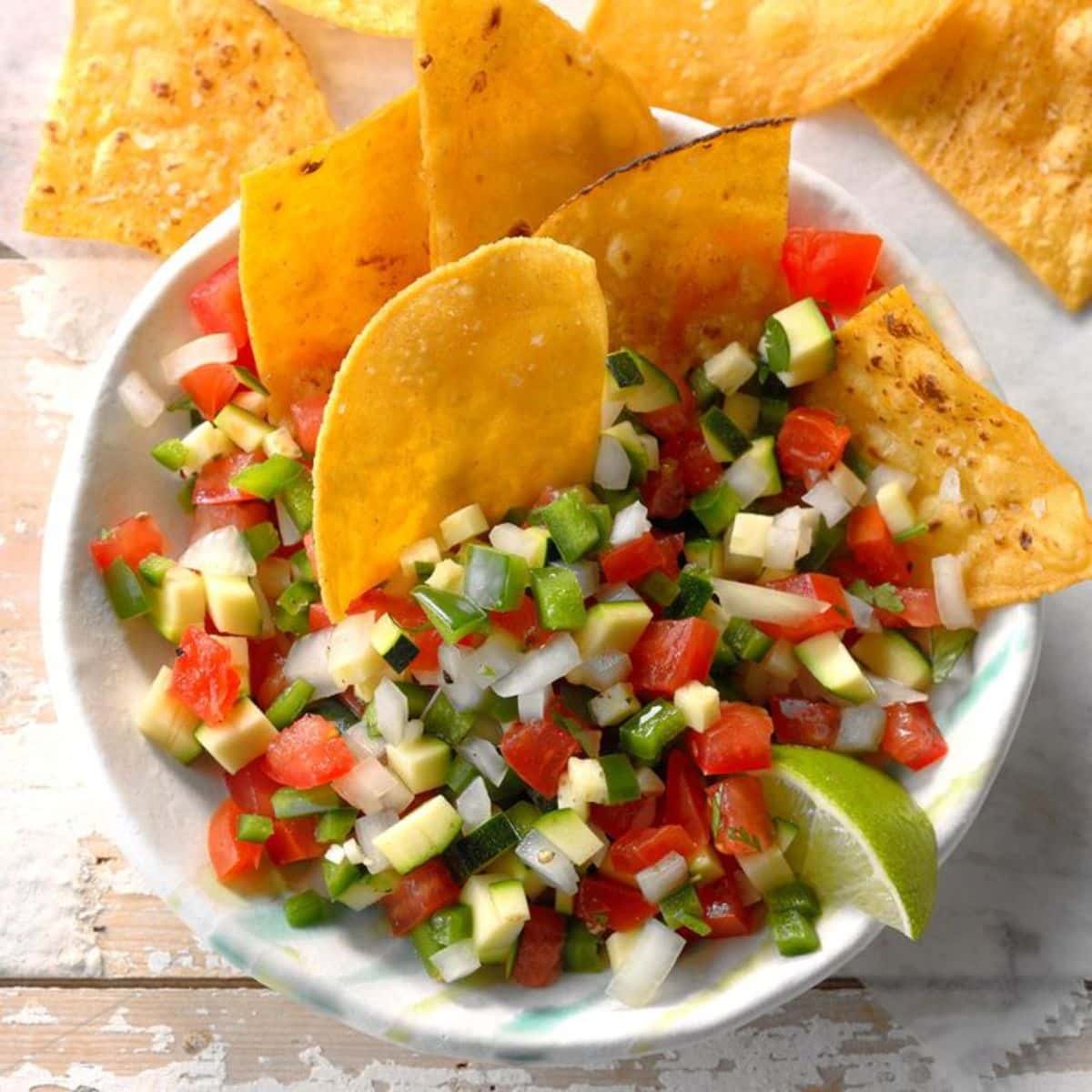 Zucchini Pico de Gallo Salsa with chips in a white bowl.