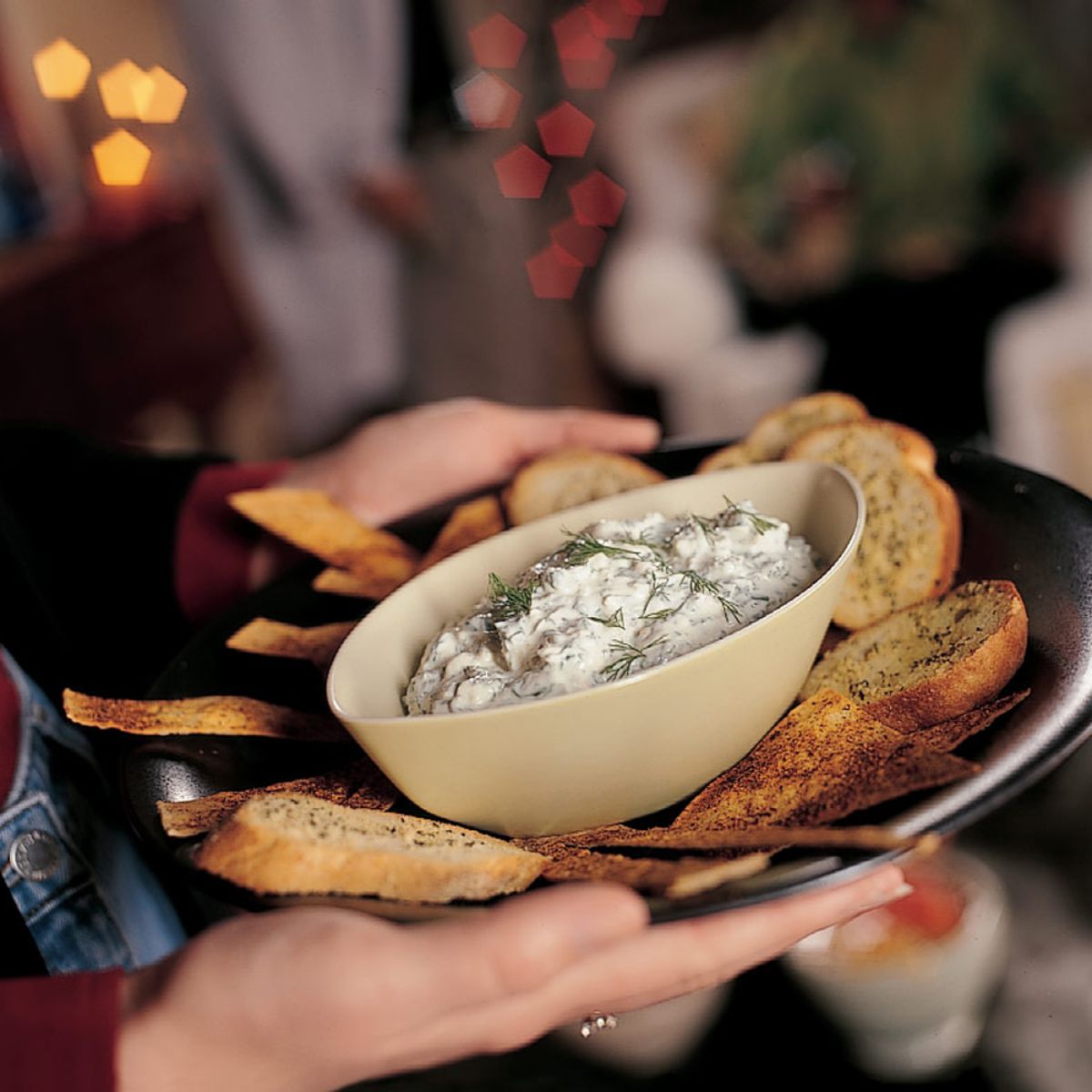 Feta Spinach Dip in a cream bowl on a tray with sliced bread and chips.