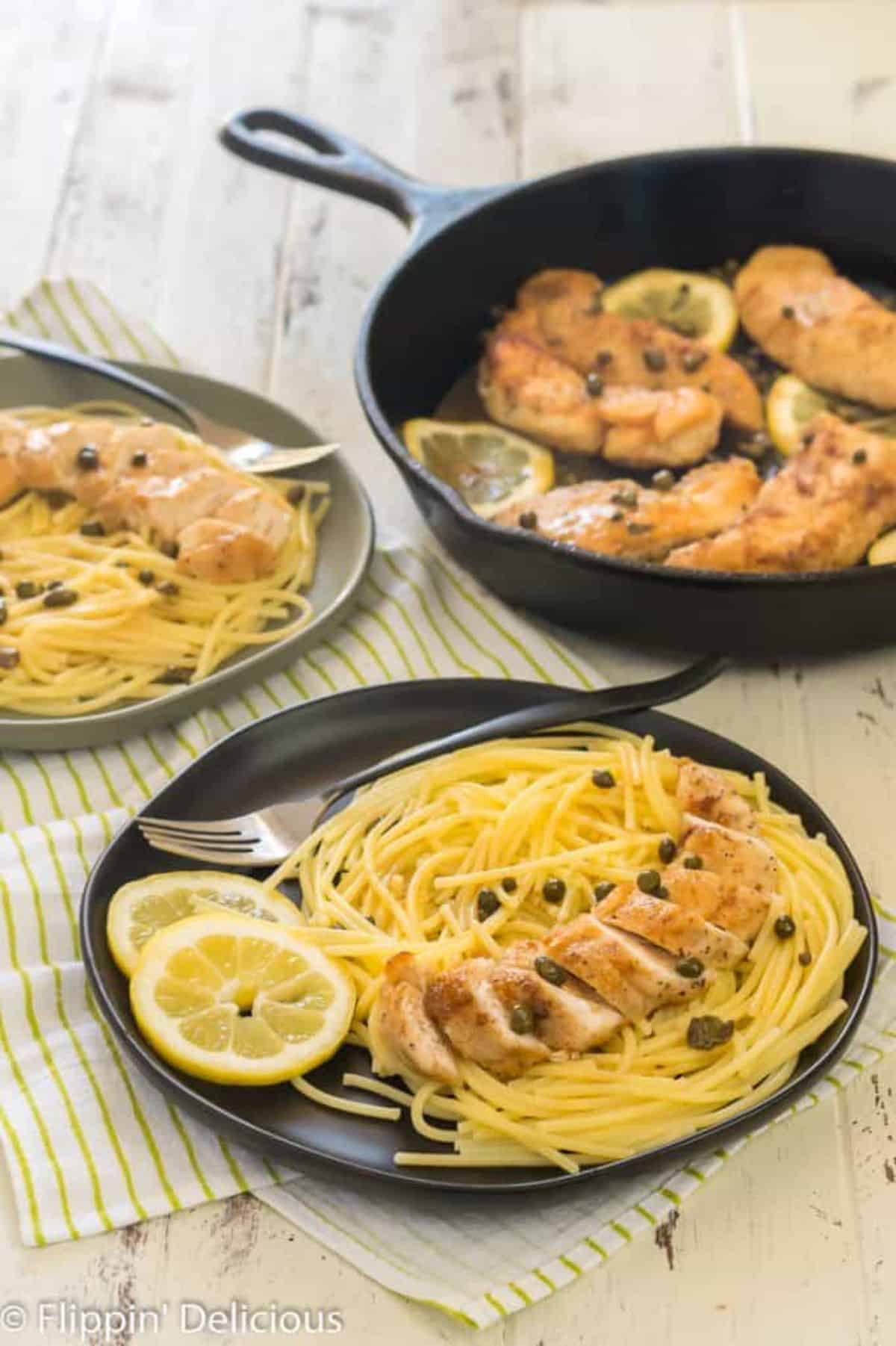 Gluten-free Chicken Piccata on a black palte with a fork.