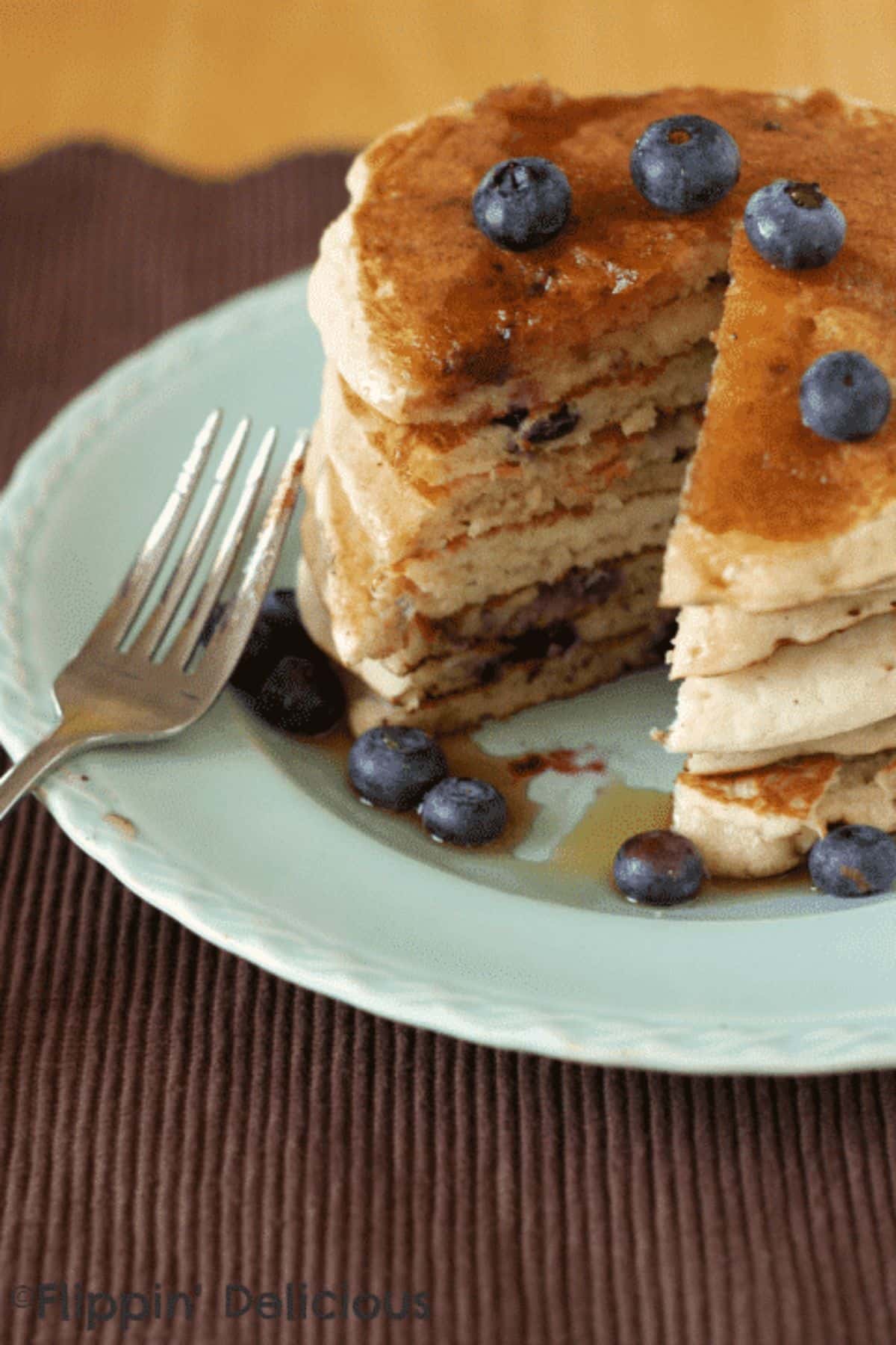 A pile of Gluten-free Blueberry Banana Pancakes on a blue plate with a fork.