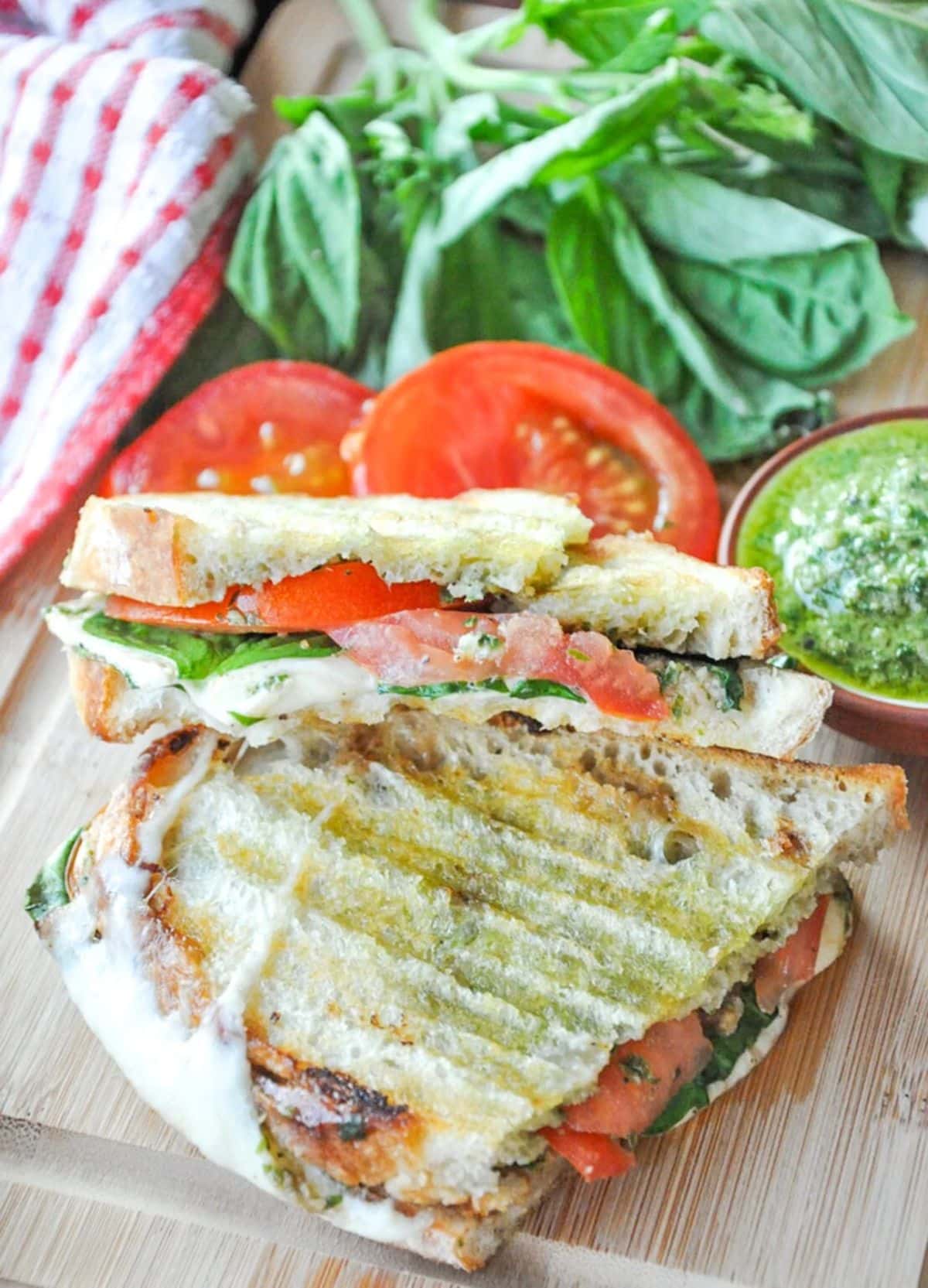 Pesto Caprese Panini sandwich on a wooden cutting baord.