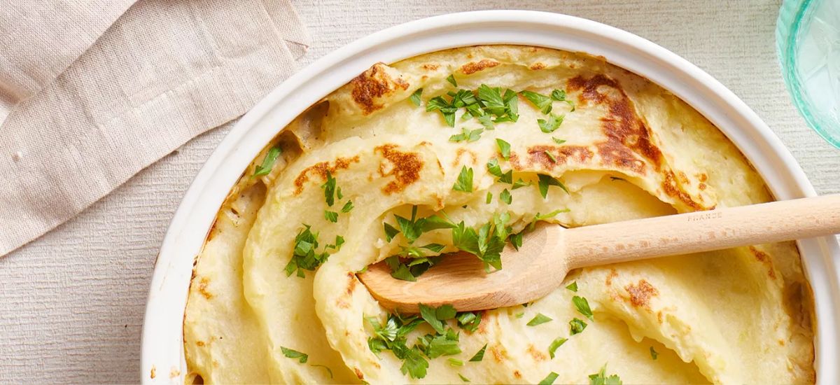 Budget-Friendly Shepherd’s Pie in a white casserole with a wooden spoon.