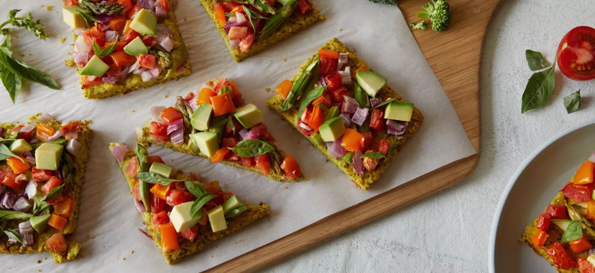 Broccoli-Crust Veggie Pizza sliced on a wooden cutting board.