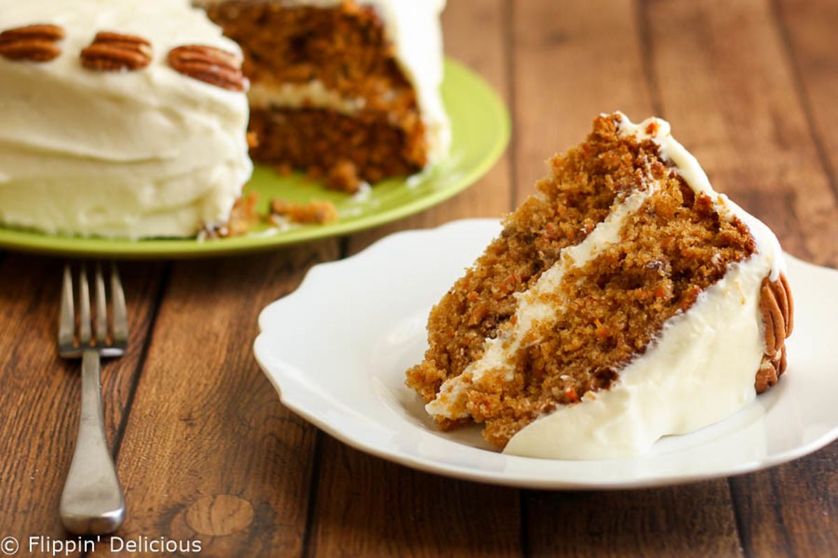 A piece of Carrot Cake with Whipped Buttercream Frosting on a white plate.