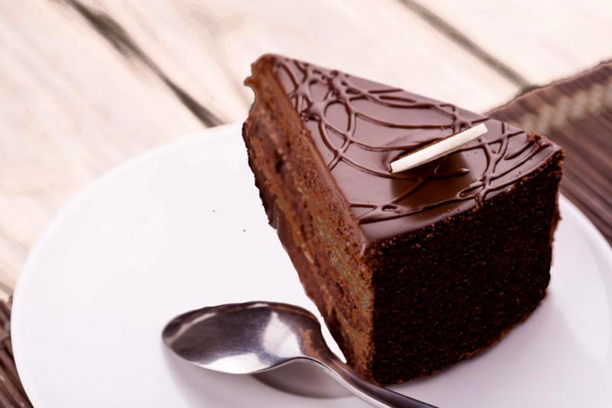 A piece of delicious Gluten-Free Blackout Cake on a white plate with a spoon.