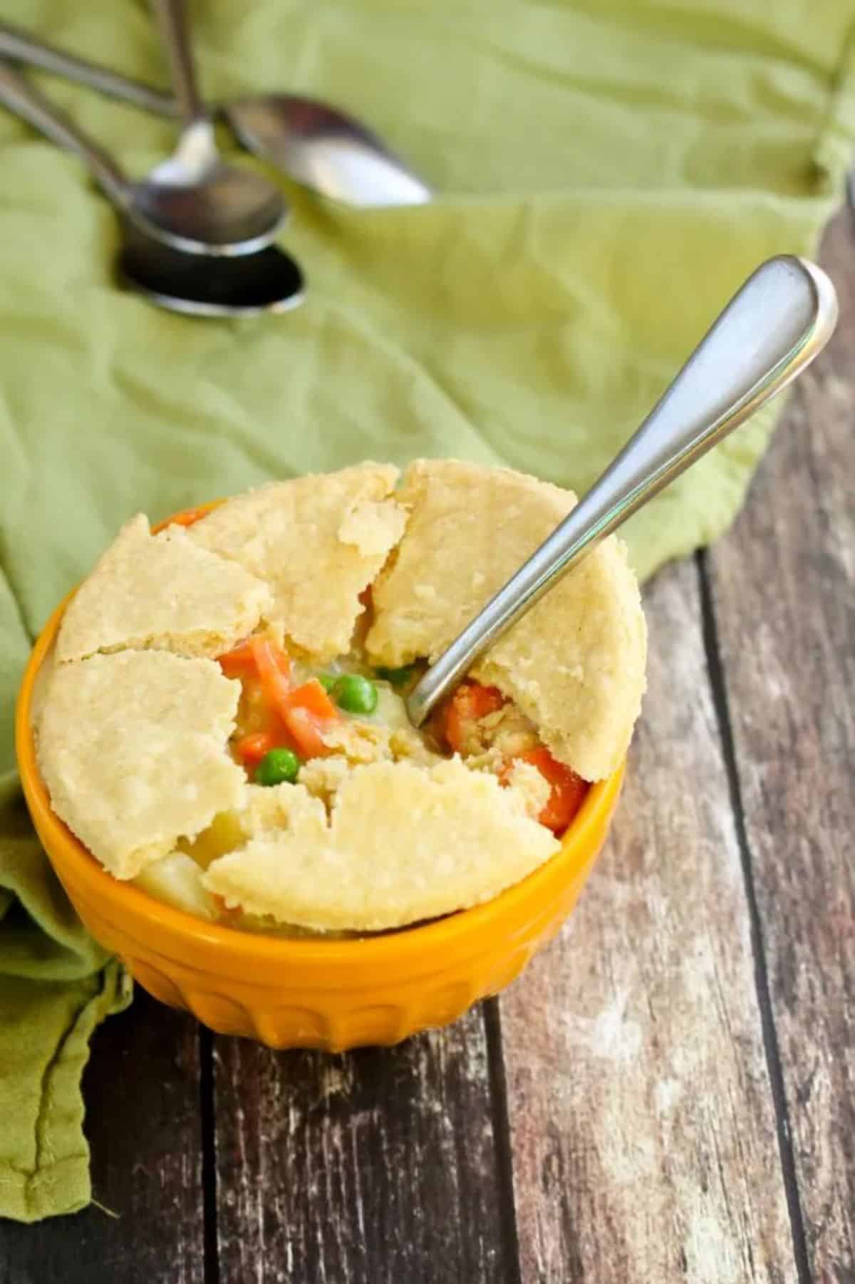 Delicious Gluten-Free Chicken Pot Pie in an orange bowl with a spoon.