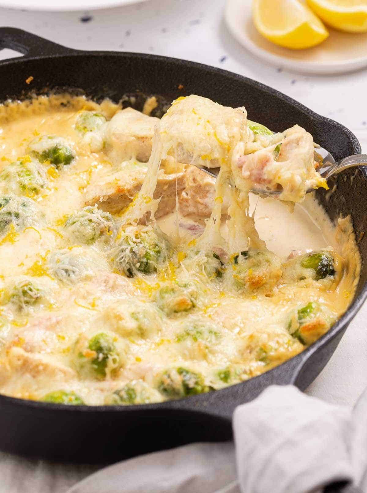 Brussels Sprouts Bacon Chicken in Parmesan Sauce in a black skillet.
