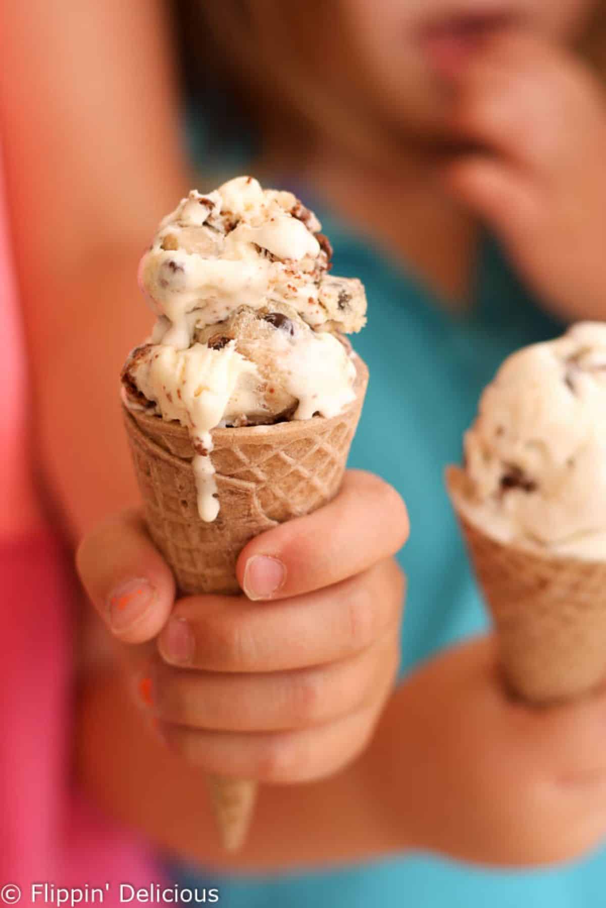 No Churn Gluten-Free Cookie Dough Brownie Ice Cream in cones held by kids.