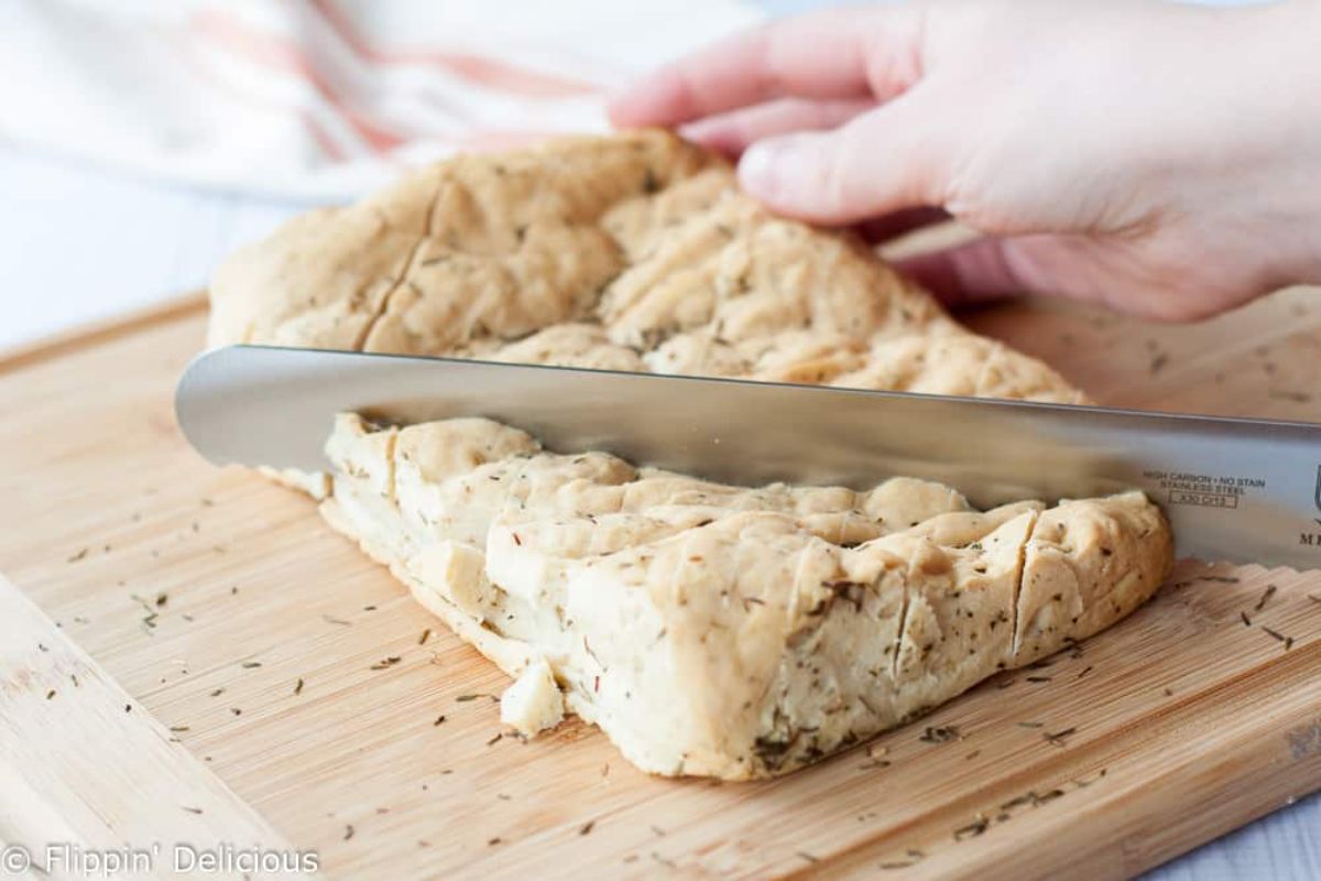 Gluten-Free Cheesy Garlic Pull-Apart Bread sliced with a knife on a wooden cutting board.