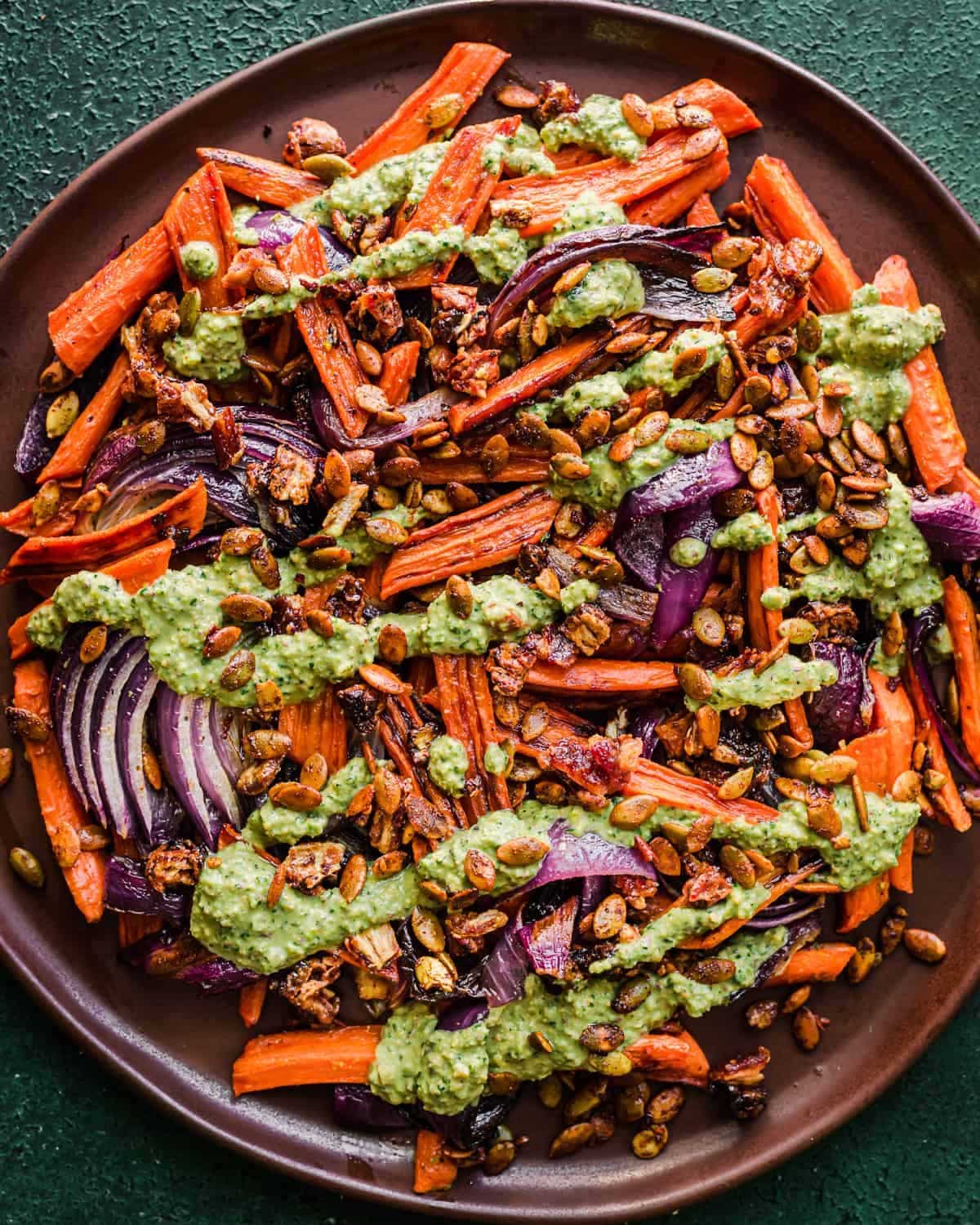 Roasted Carrots and Dates with Pistachio Pesto on a brown plate.