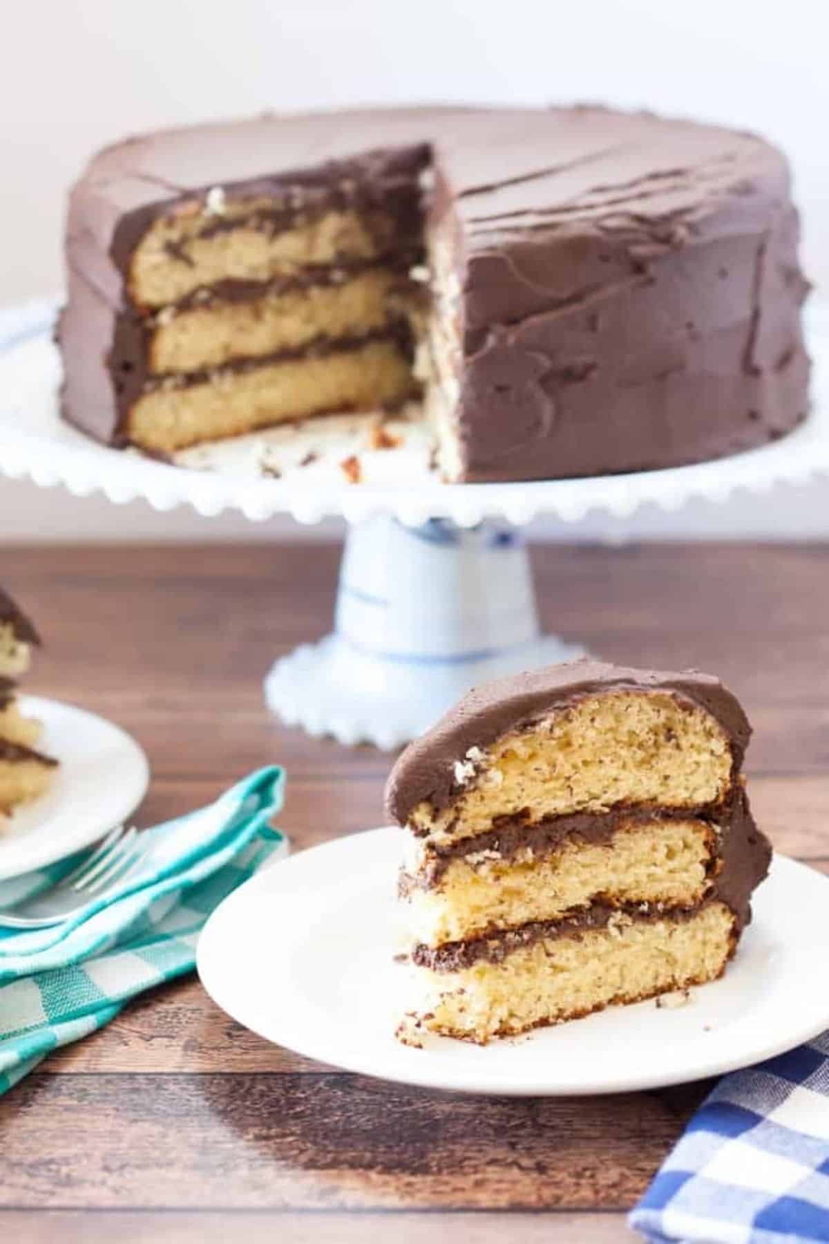 Delicious Gluten-Free Yellow Cake With Chocolate Fudge Frosting in a cake tray and on a white plate.