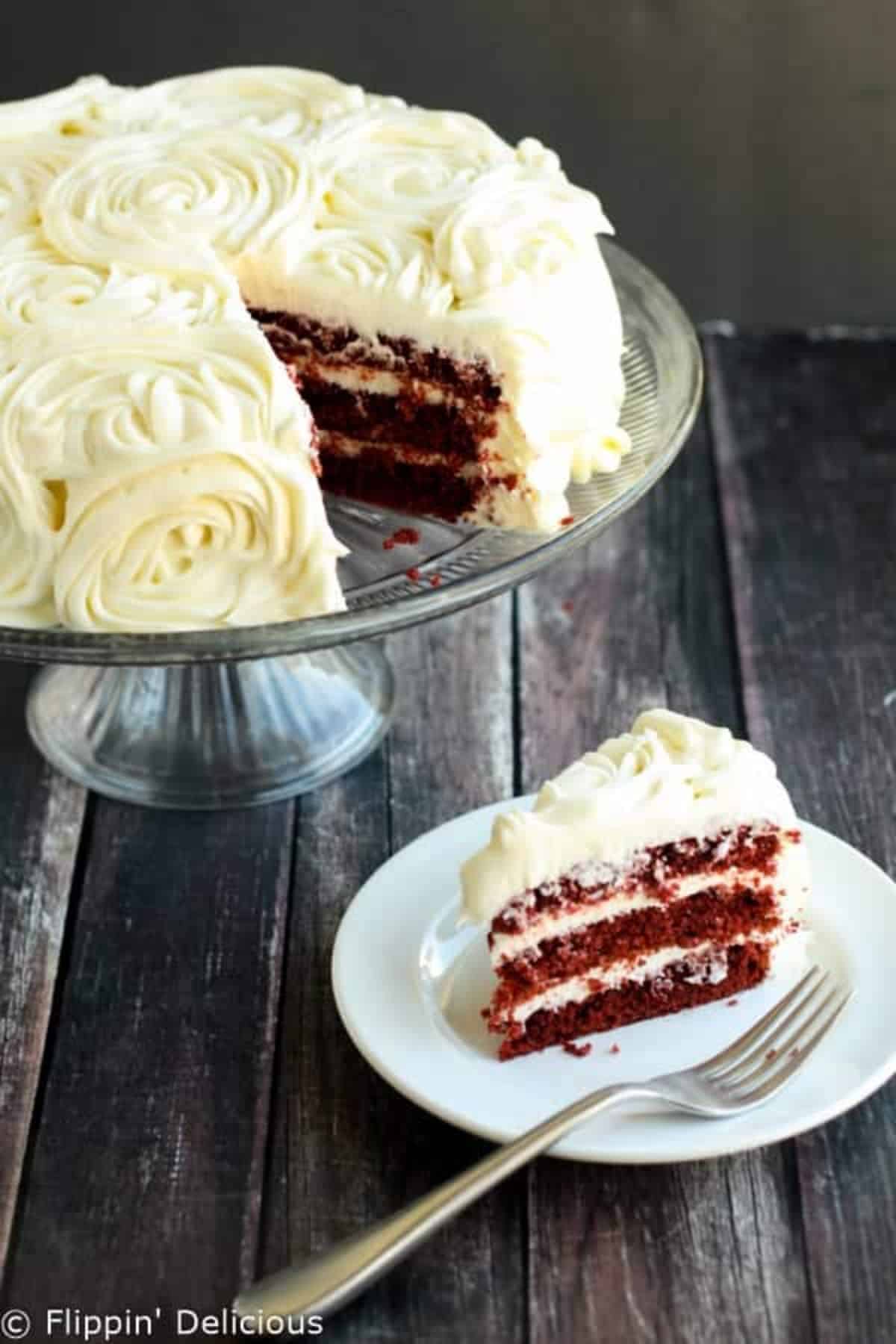 Delicious Red Velvet Cake with Cream Cheese Frosting on a glass cake tray and on a white plate.