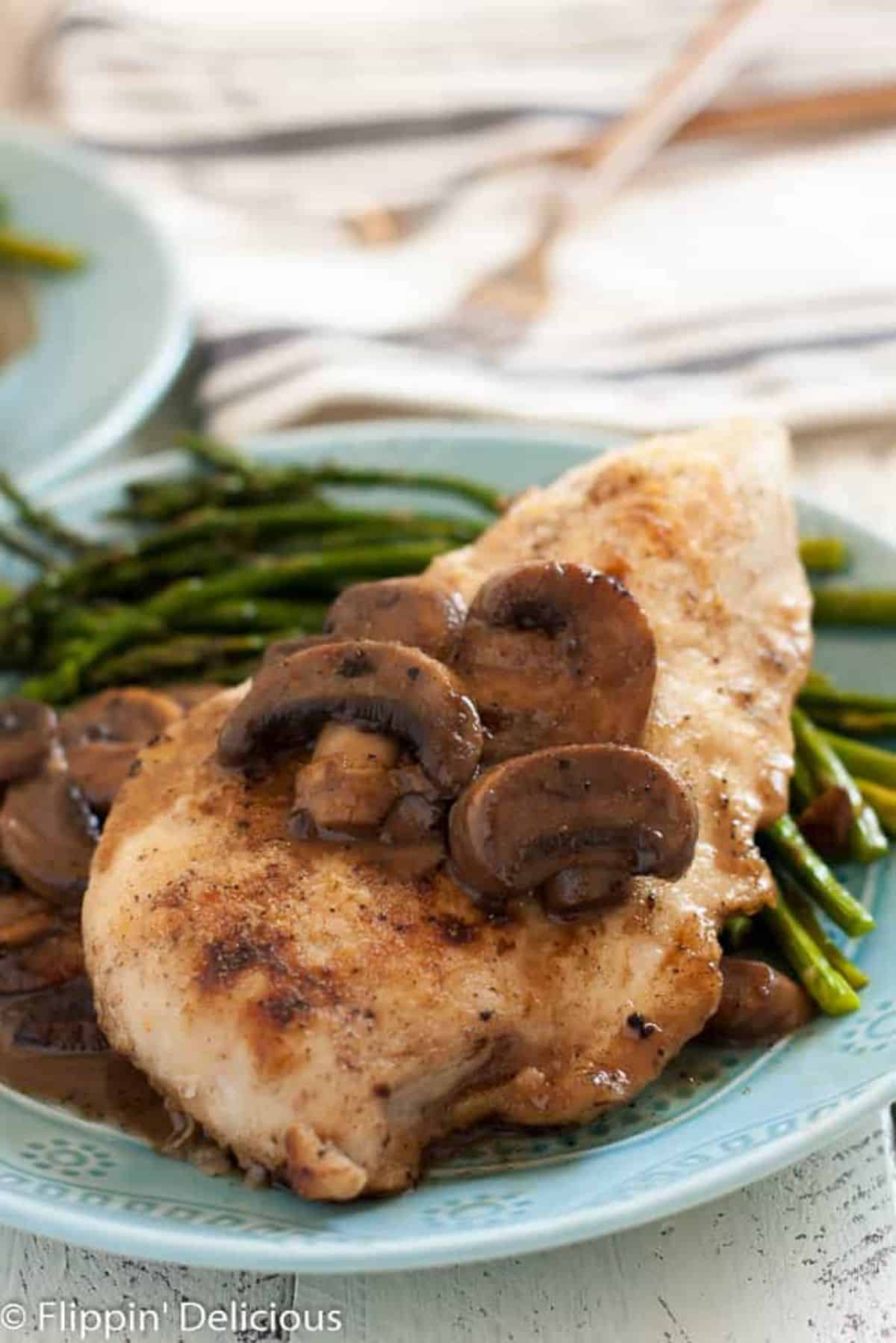 Gluten-Free Chicken Marsala with veggies on a blue plate.