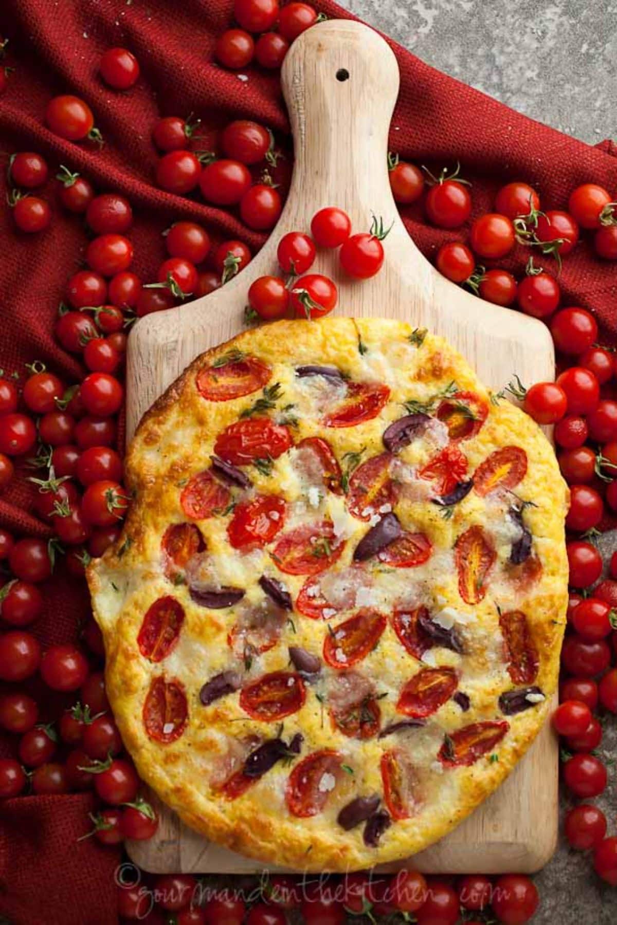 Gluten-Free Tomato Olive Focaccia Bread on a wooden cutting board.