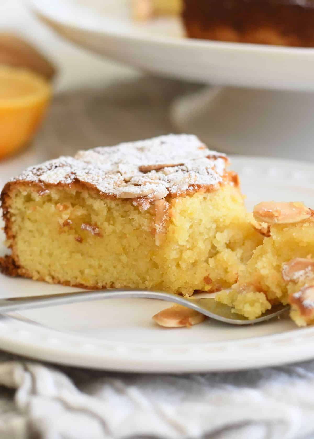 A piece of Italian Gluten-Free Almond, Orange Cake on a white plate with a fork.